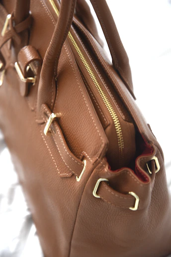 Close-up of a brown leather handbag with gold hardware.