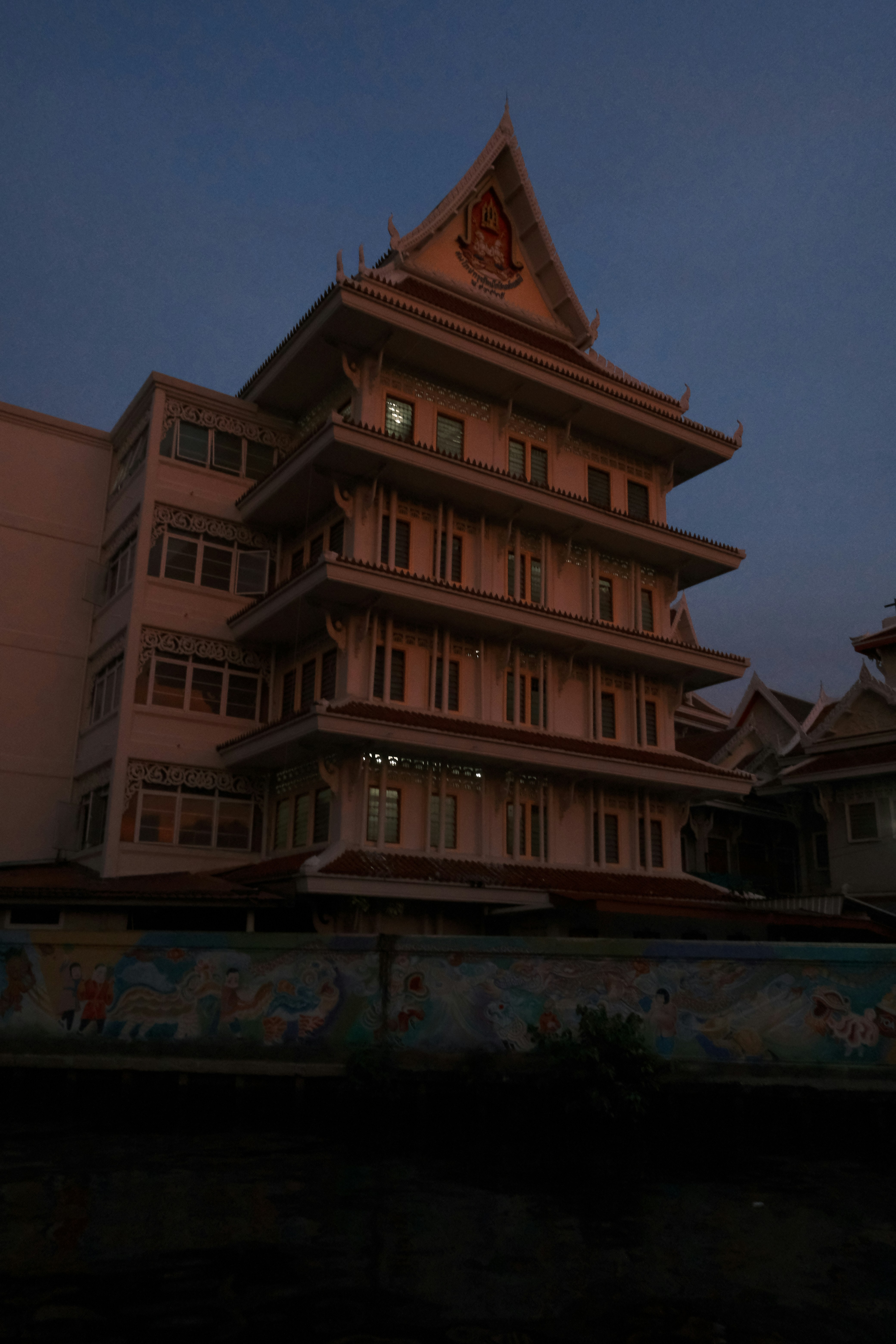 A multi-story building with ornate roof details at dusk.