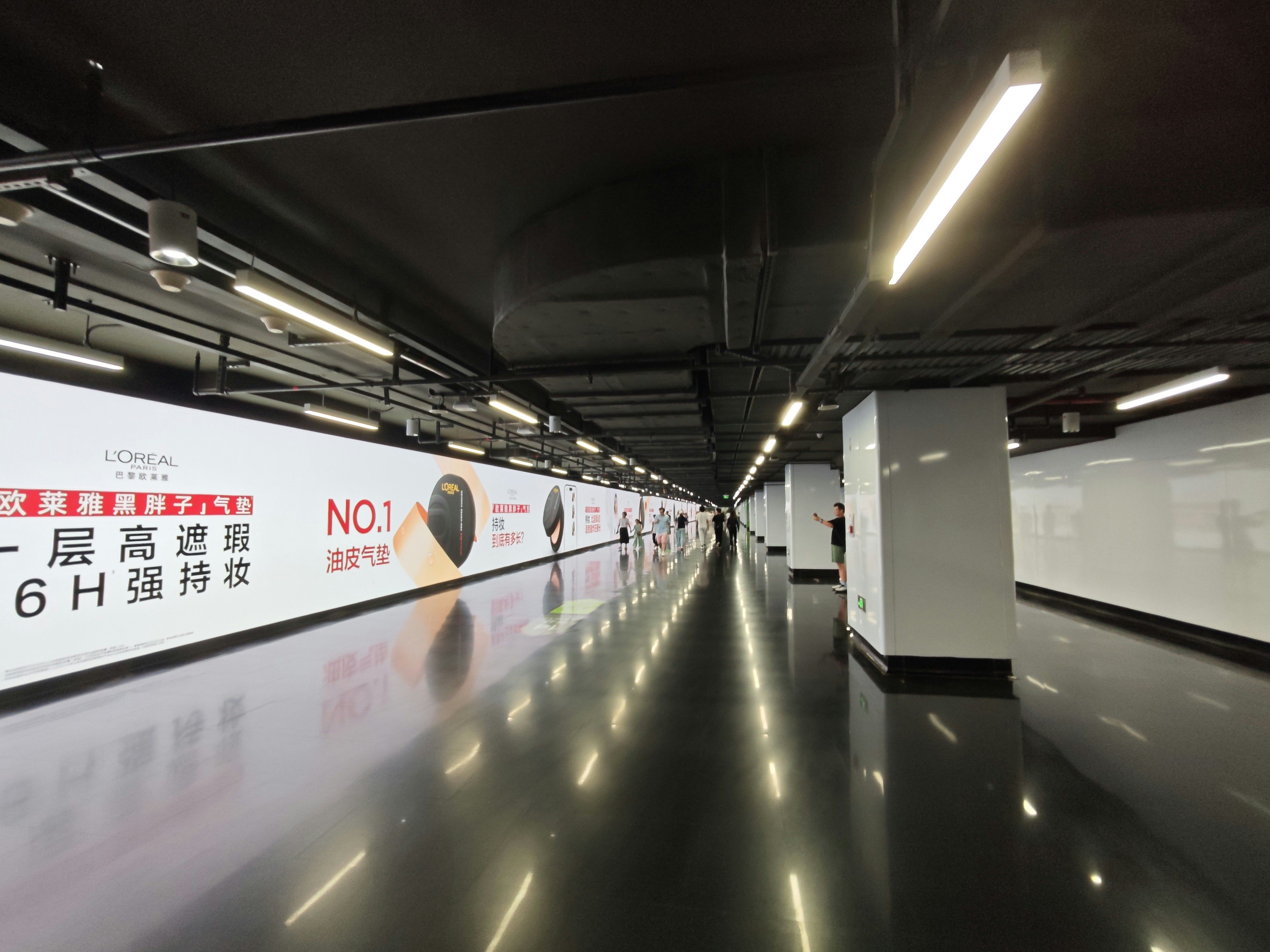 Modern illuminated hallway with reflective floor and advertisements