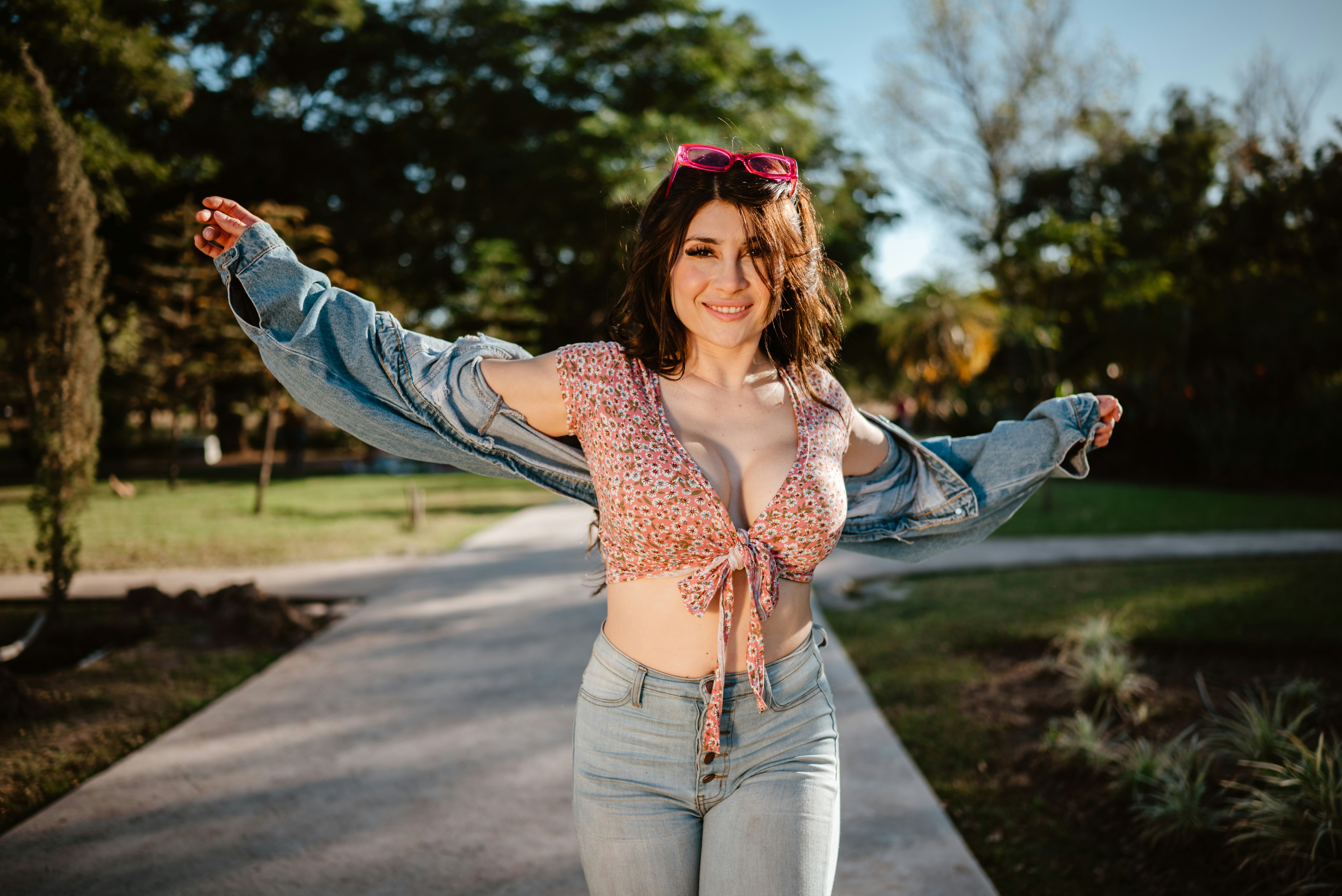 A woman in a crop top and jeans walks outdoors.