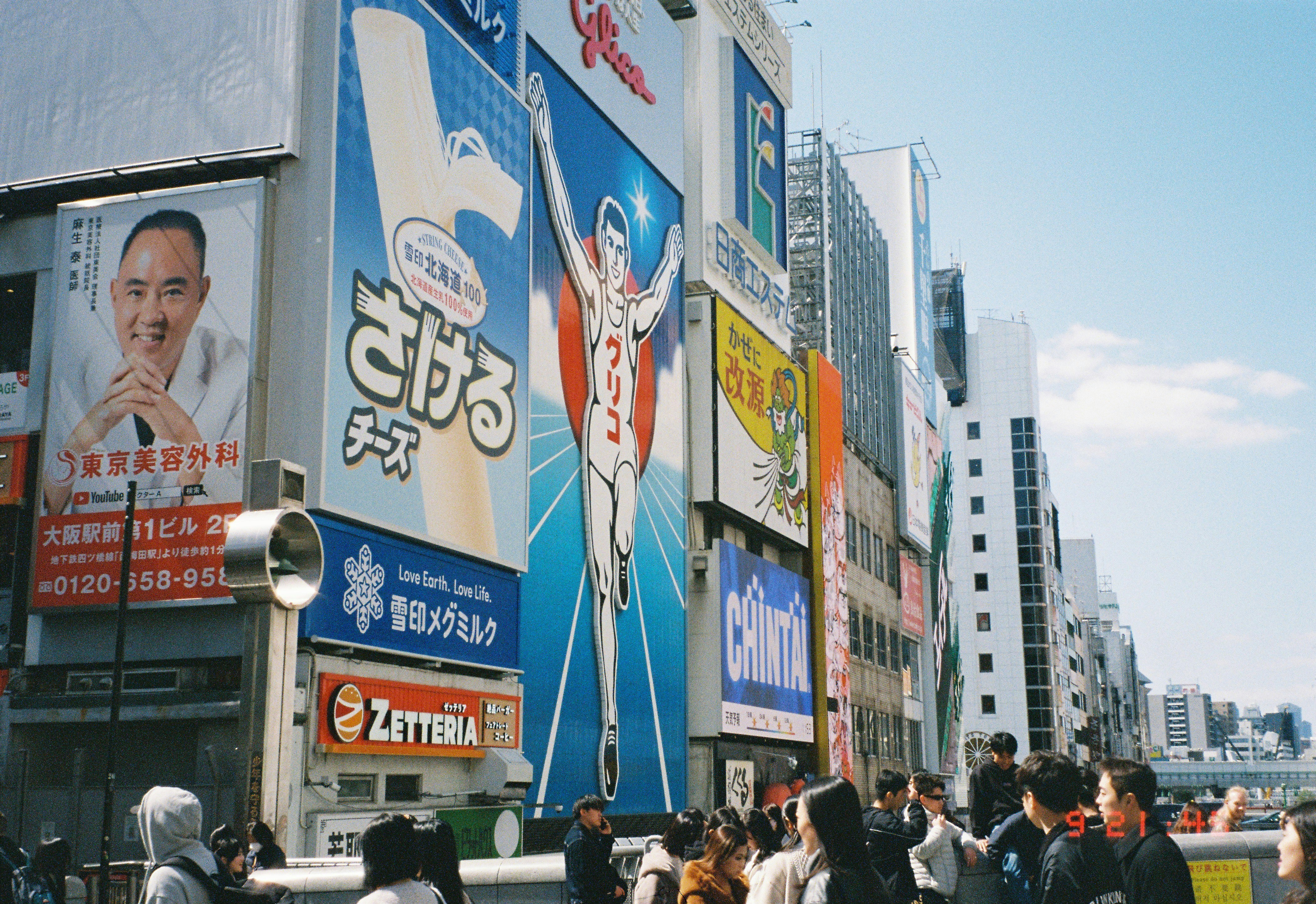 Street scene with large advertisements and people.