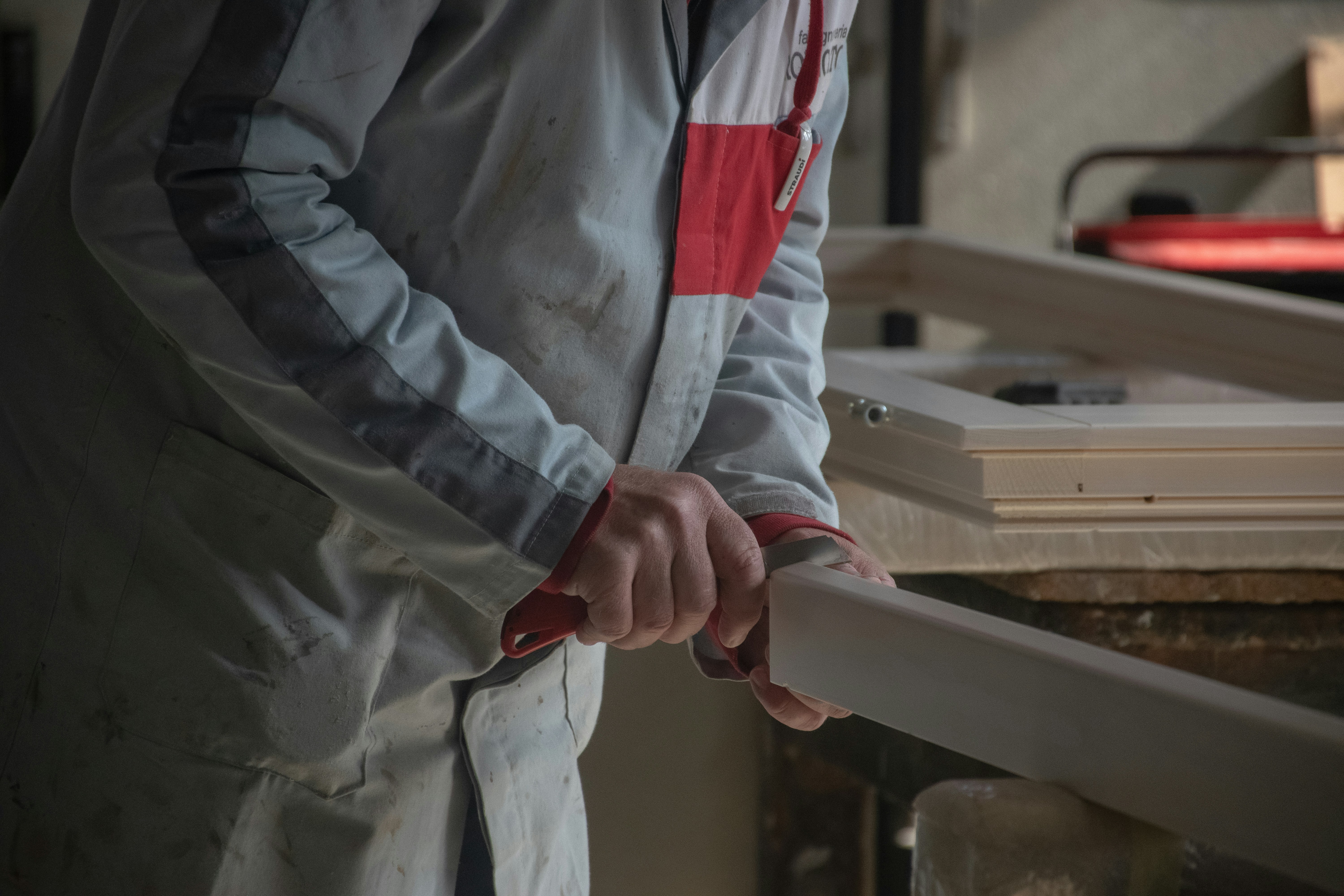 Carpenter shaping wood with a tool.
