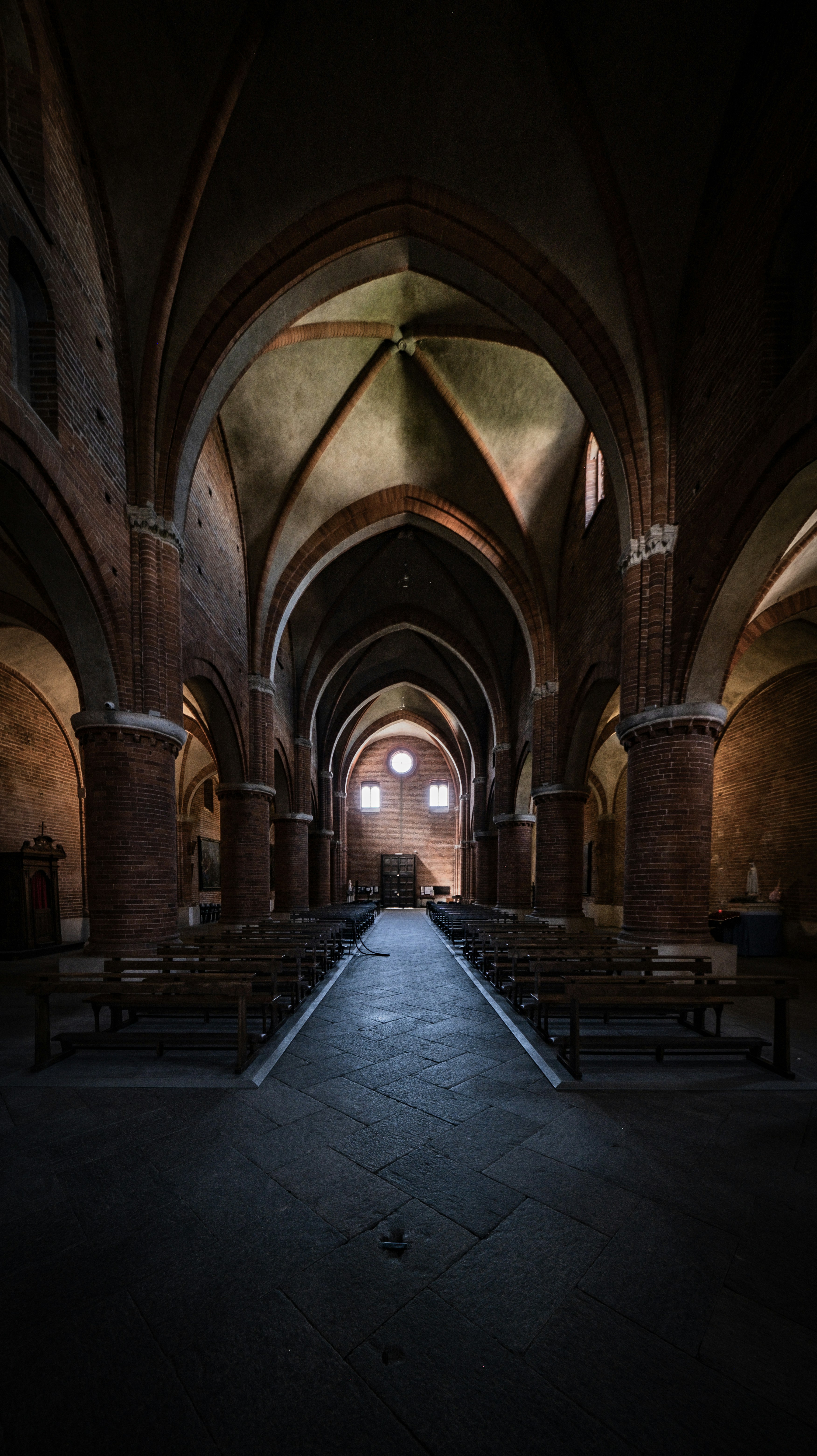 Intérieur d’une église sombre et vide aux plafonds voûtés.