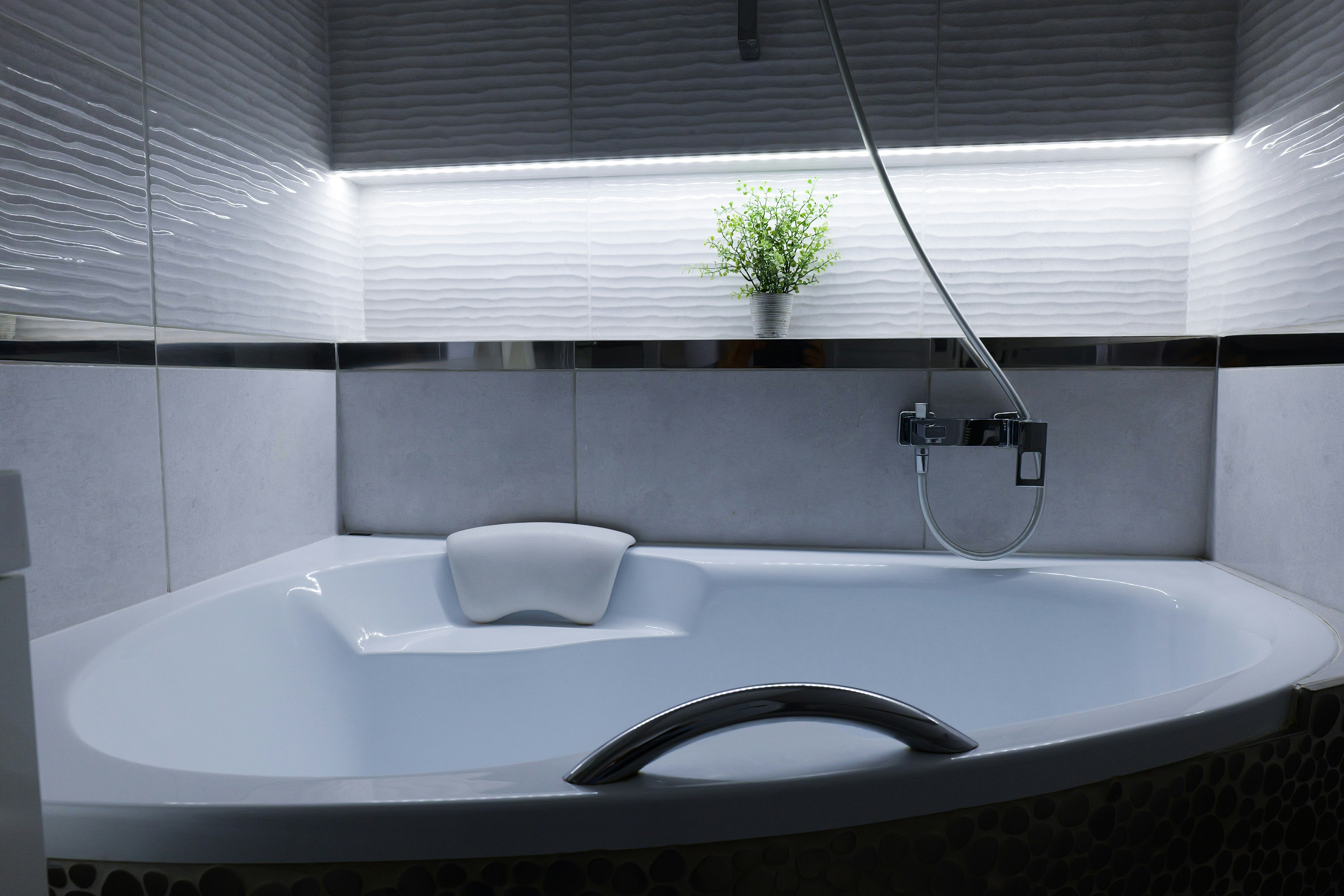 小さな植物が置かれた現代的なコーナーバスタブ。