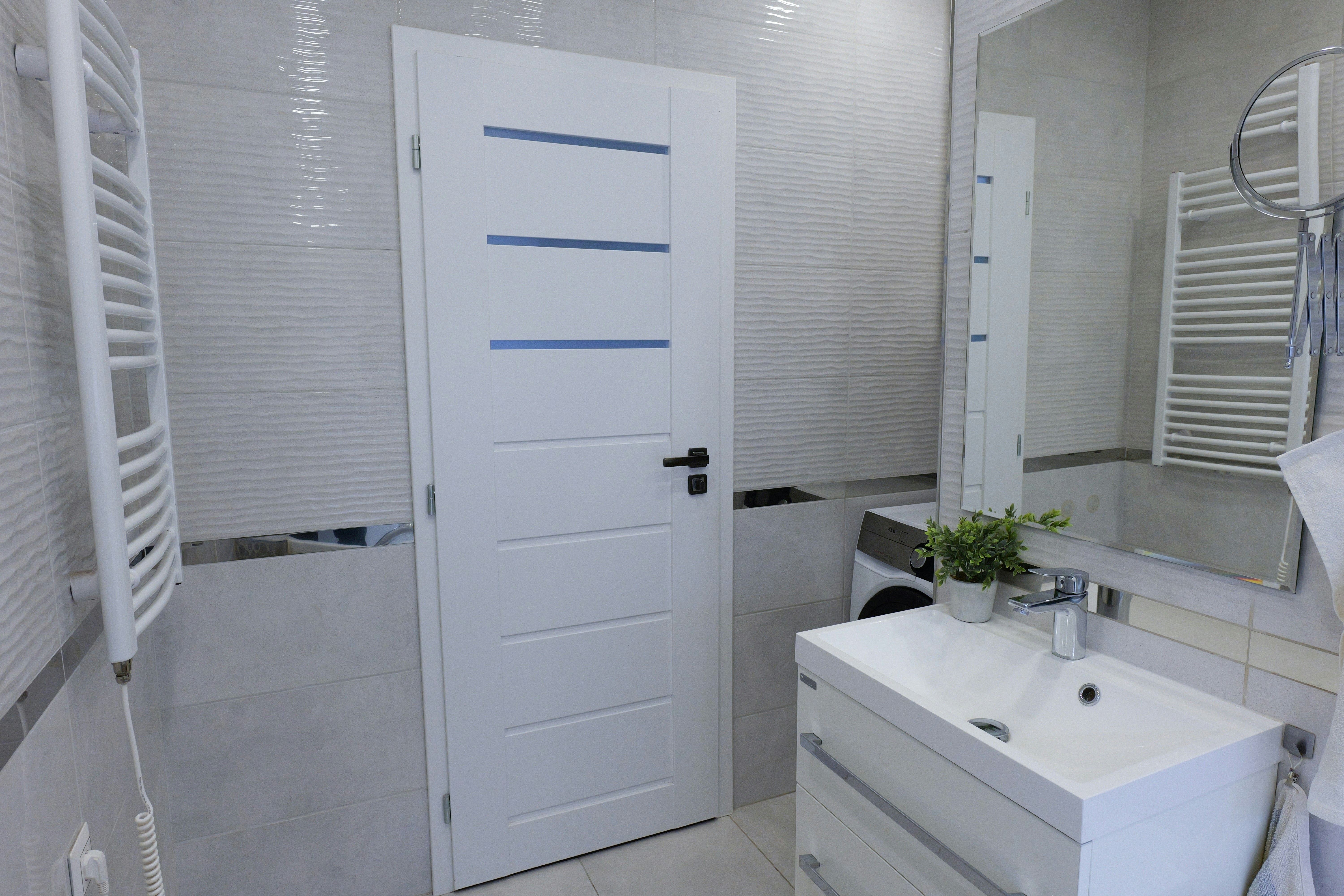 洗面台、鏡、ドア付きのモダンなバスルーム。