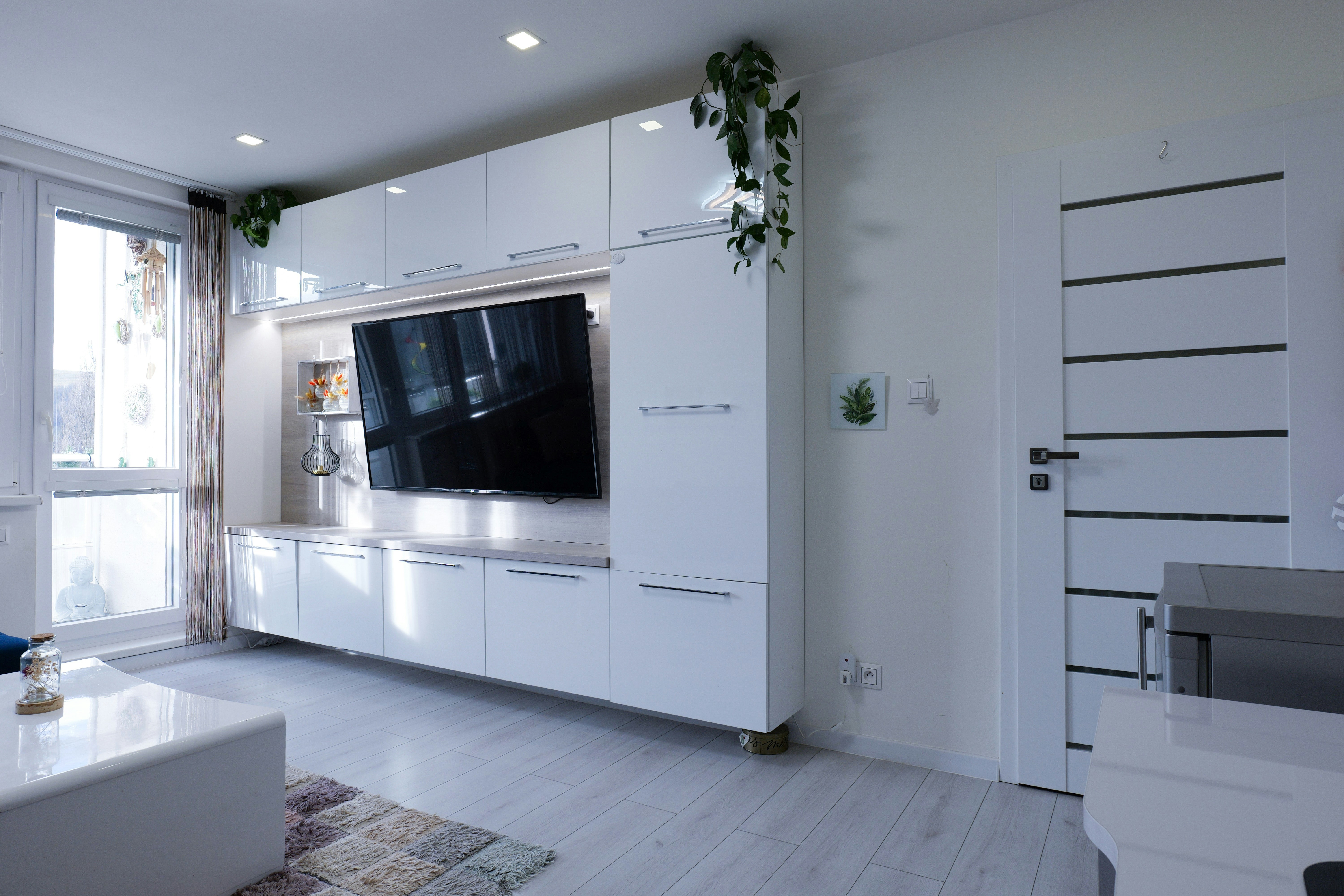 白いエンターテインメントユニットとテレビを備えたモダンなリビングルーム。