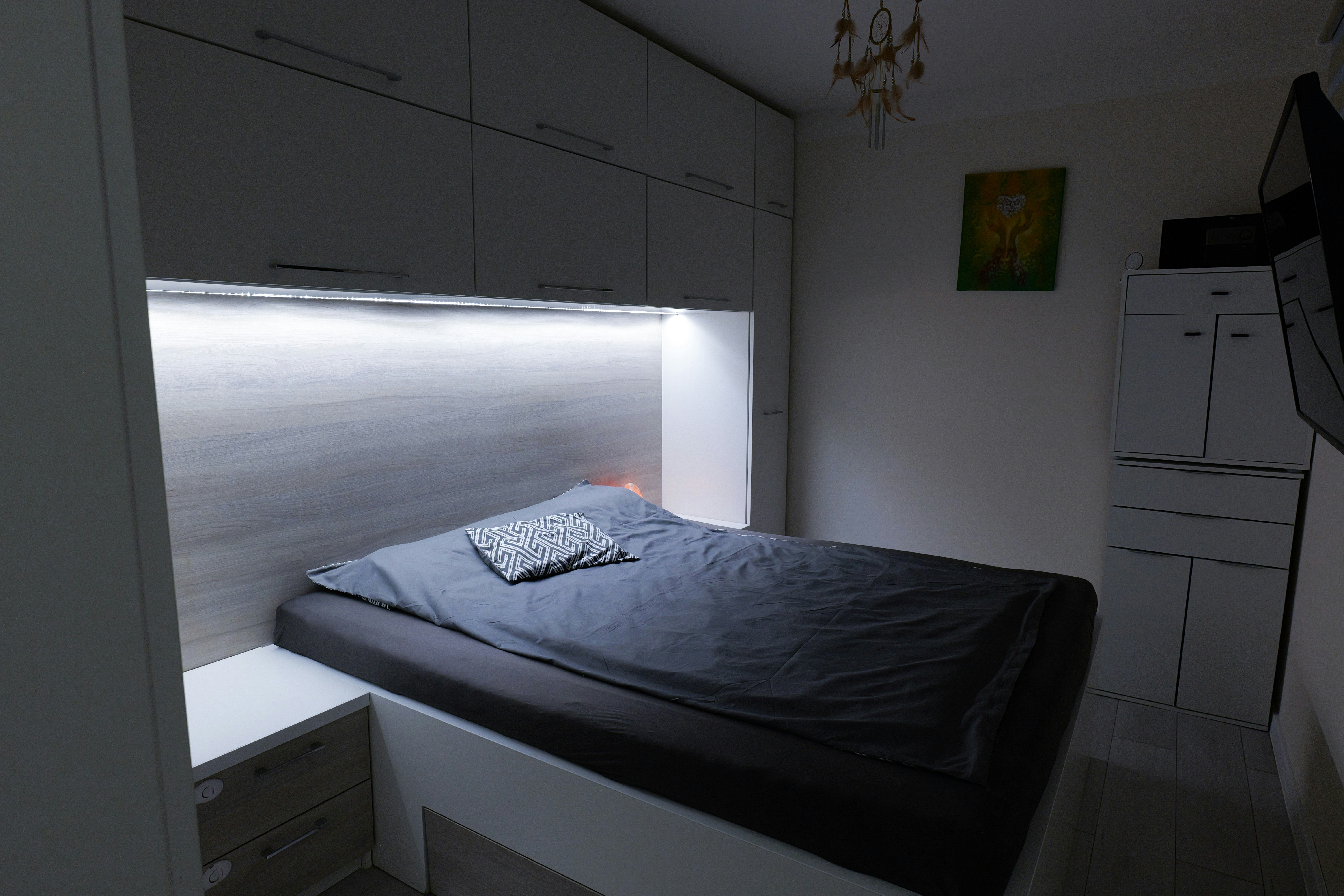 A modern bedroom with a bed and built-in lighting.