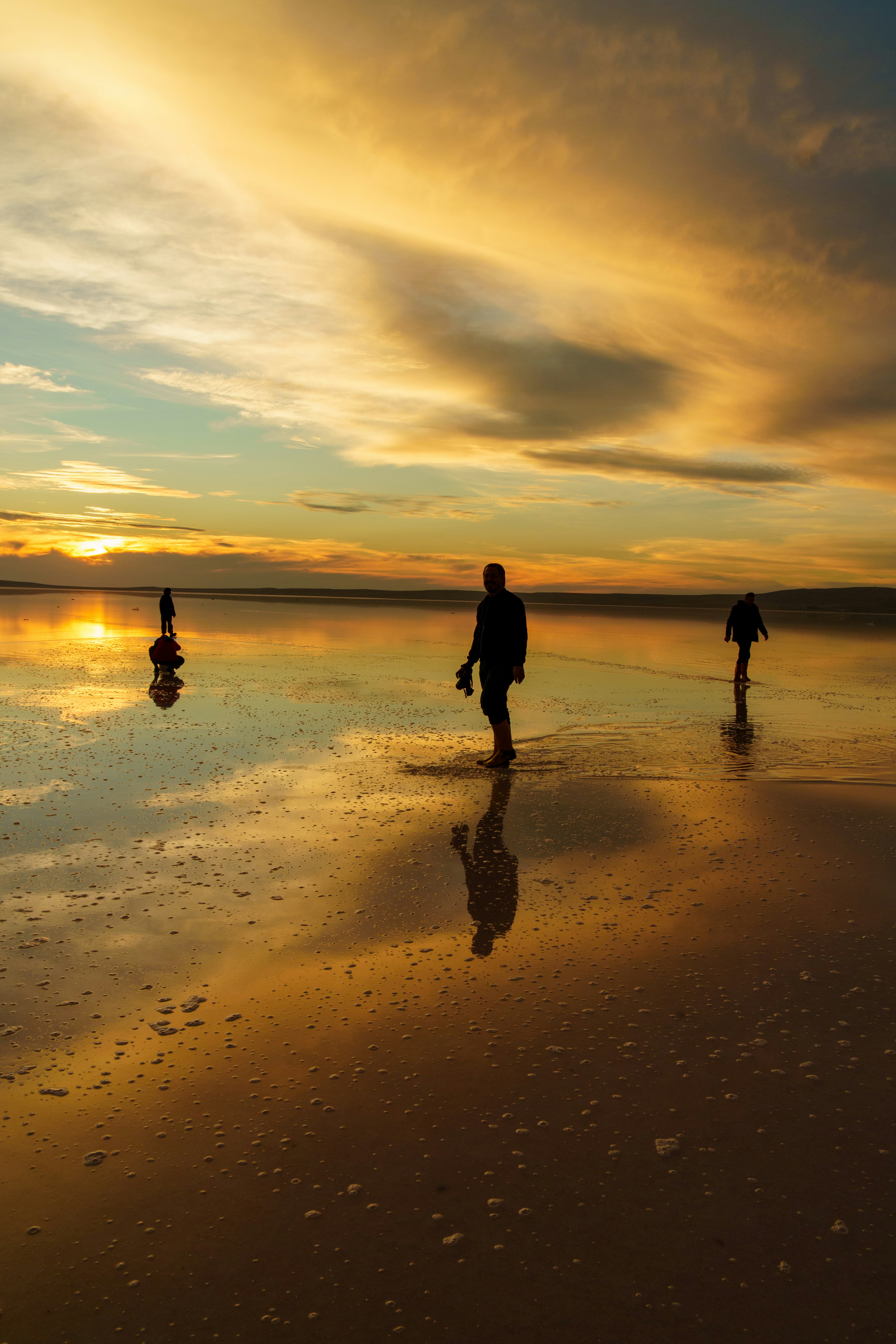 People walking on a reflective surface at sunset