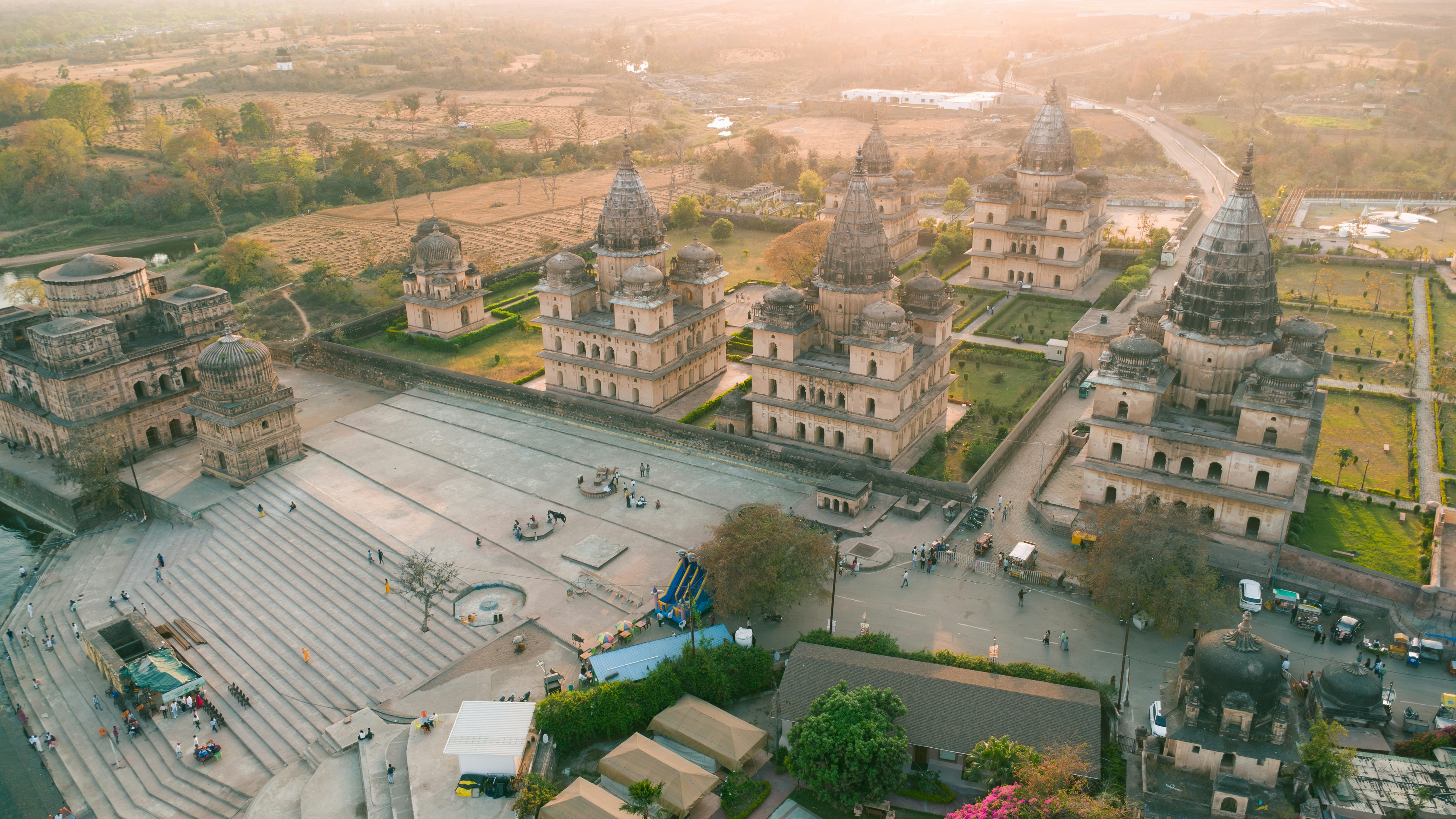 An aerial view of a sprawling ancient Indian temple complex surrounded by modern urban development, highlighting the contrast and value of the land.