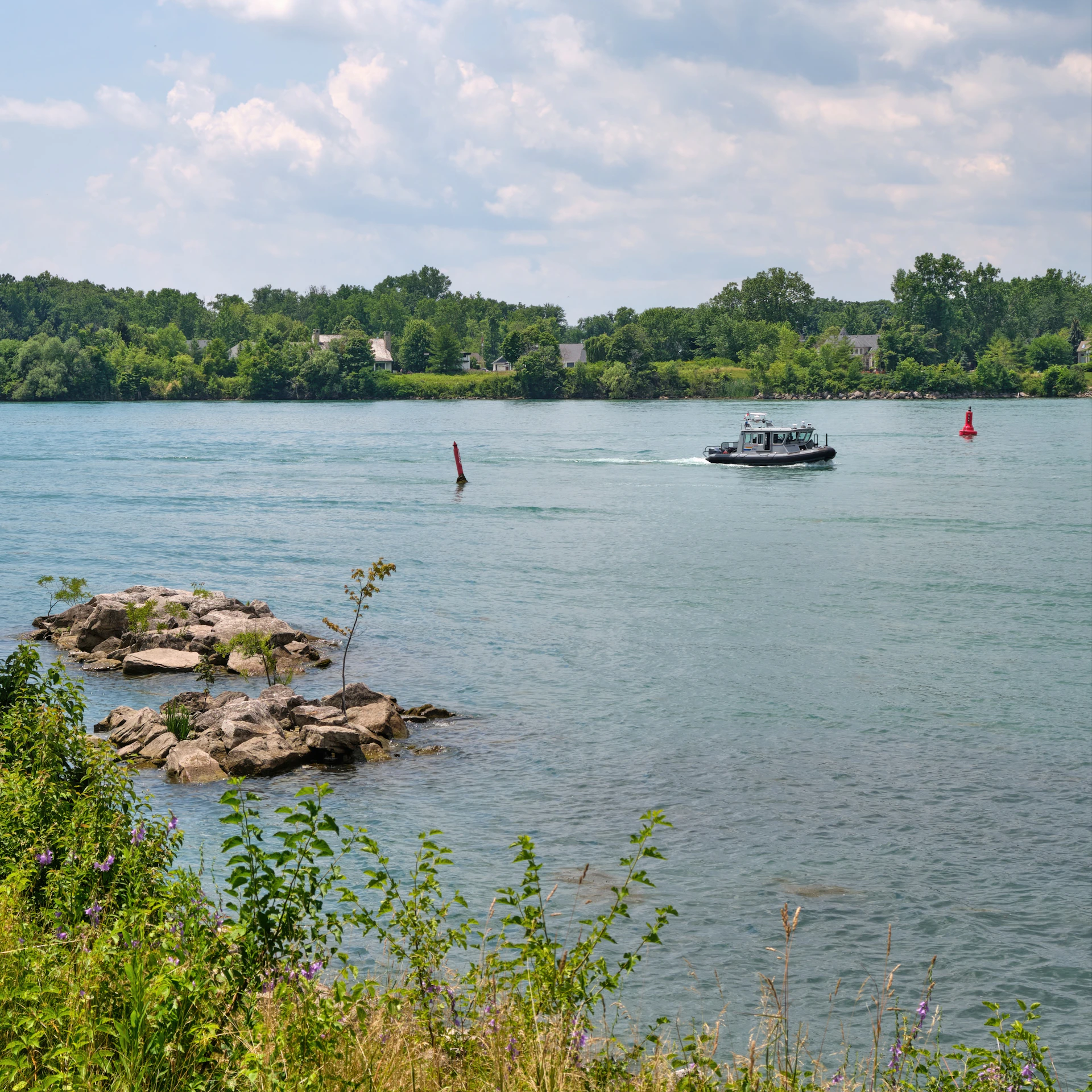 A small boat sails across a wide, calm river.