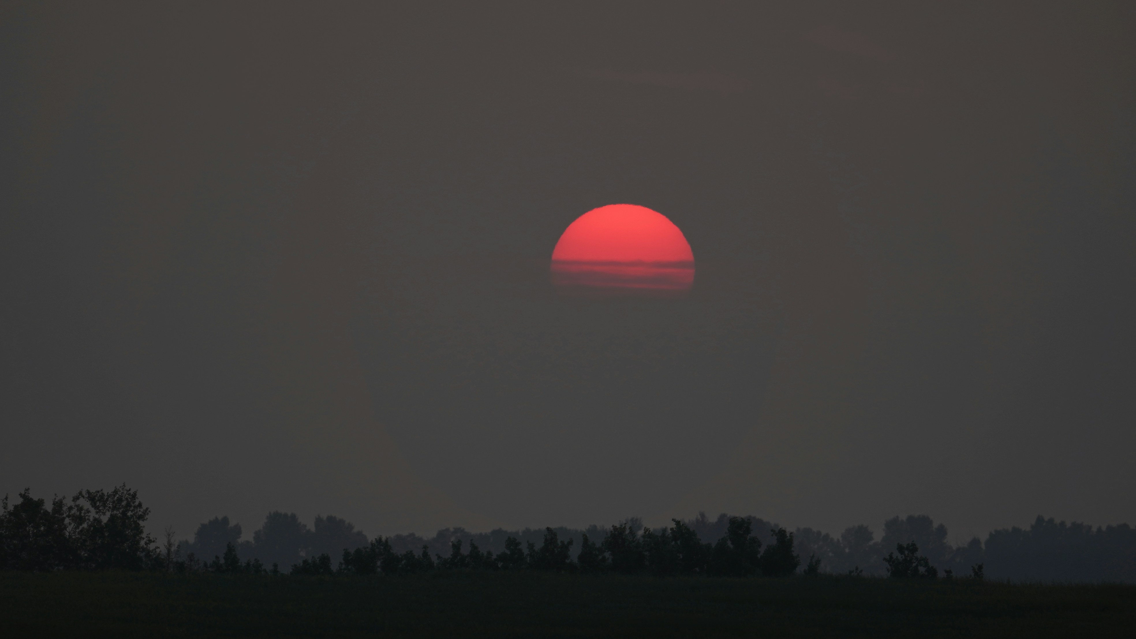 Red sun setting over a silhouetted landscape