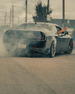 Black car doing a burnout with smoke billowing out