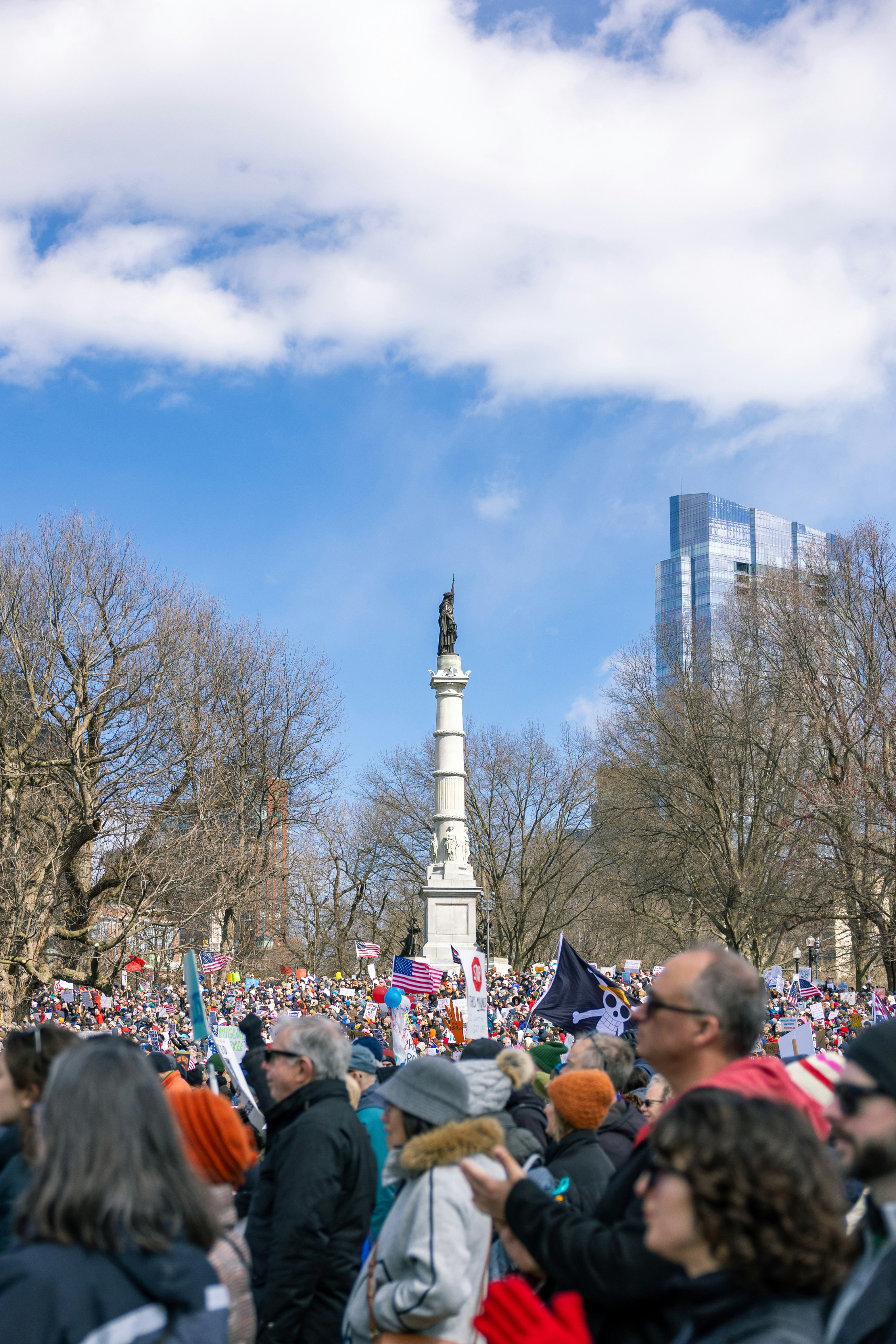 Crowd gathered around a monument with modern buildings behind