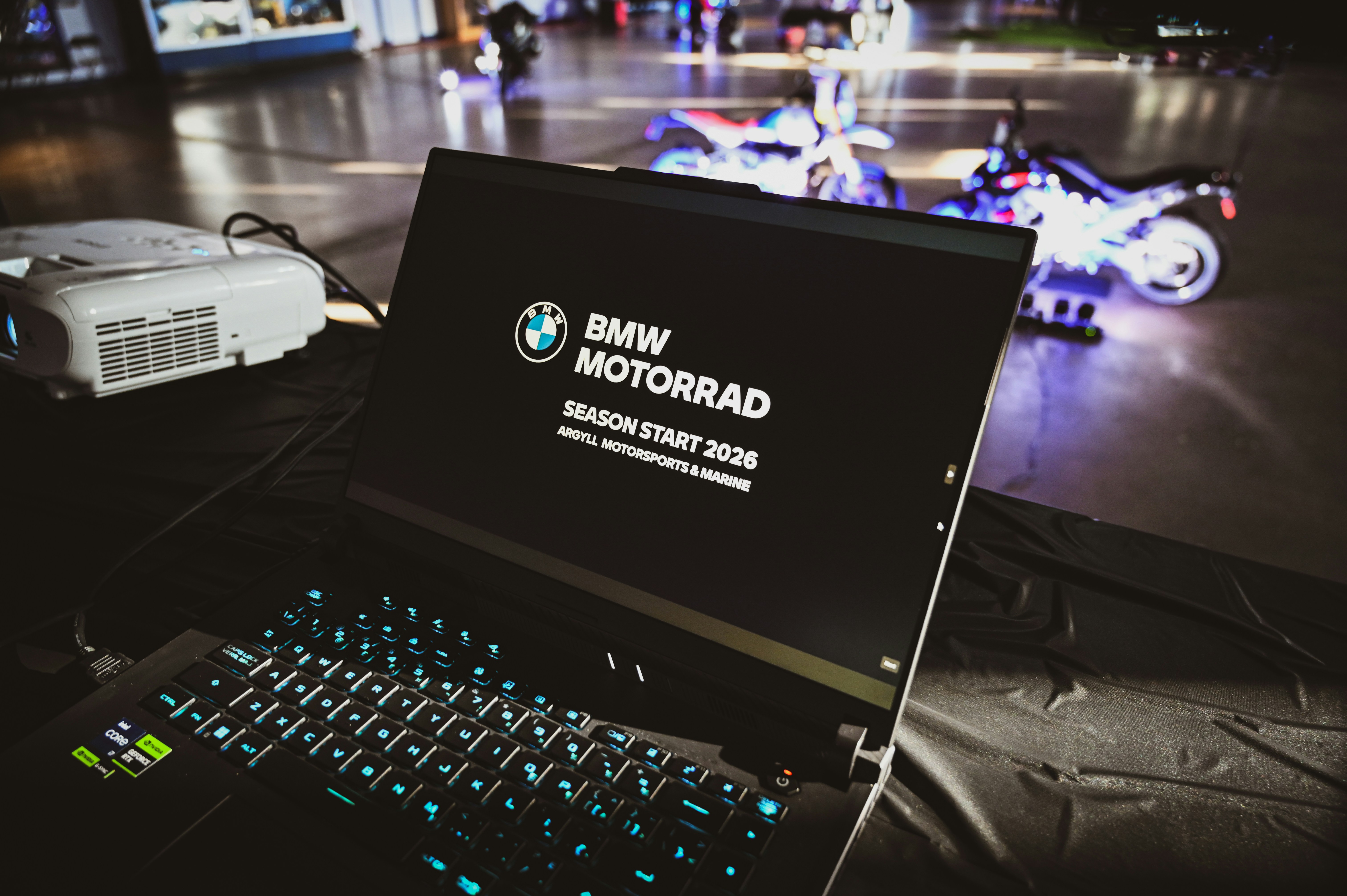 Laptop mit dem BMW Motorrad-Logo und Motorrädern im Hintergrund