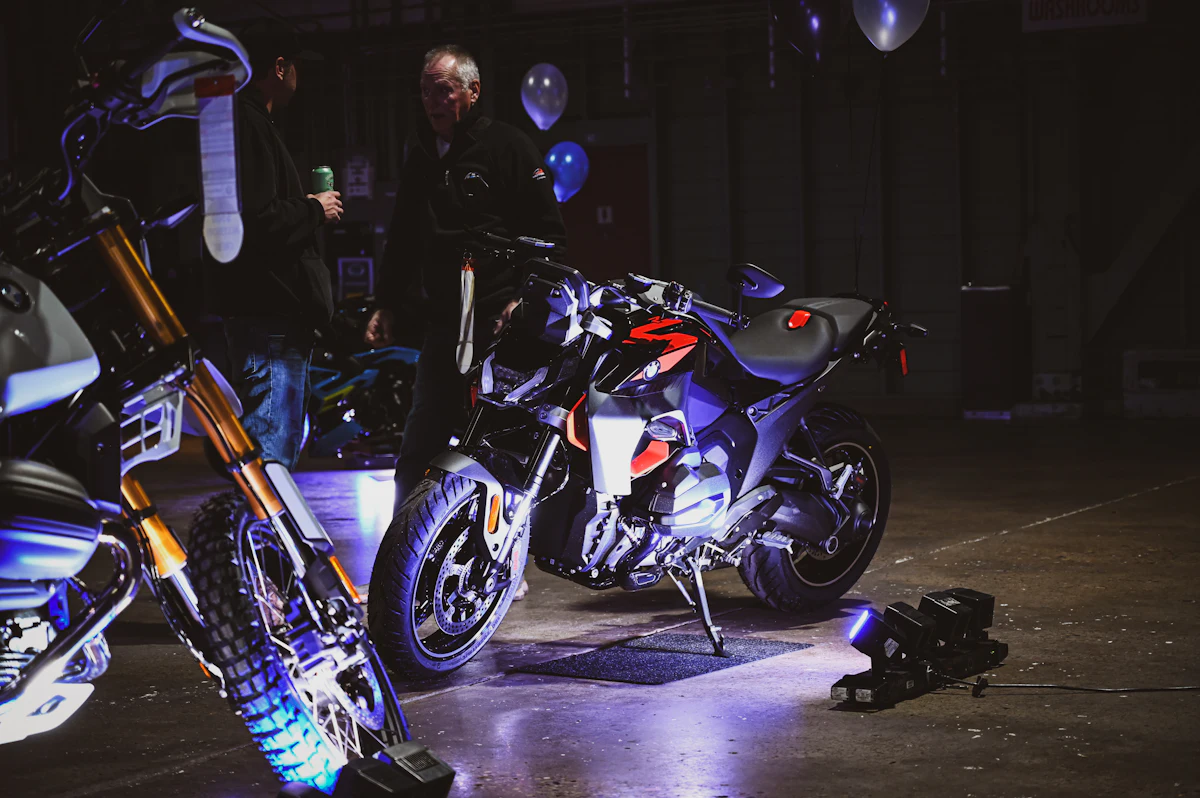 Two motorcycles on display under blue and purple lights in a dark hall