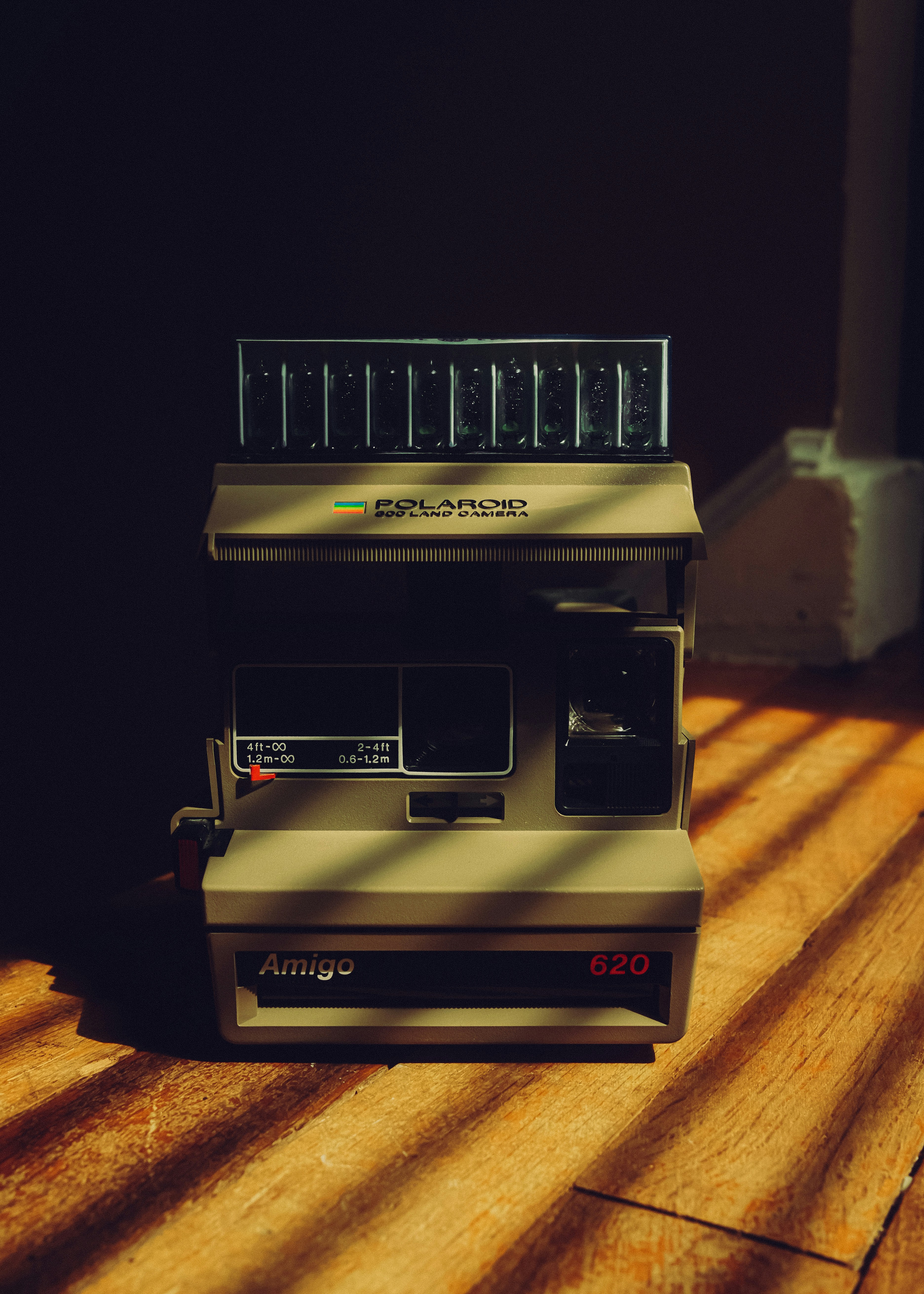 Vintage polaroid camera on a wooden surface with shadows
