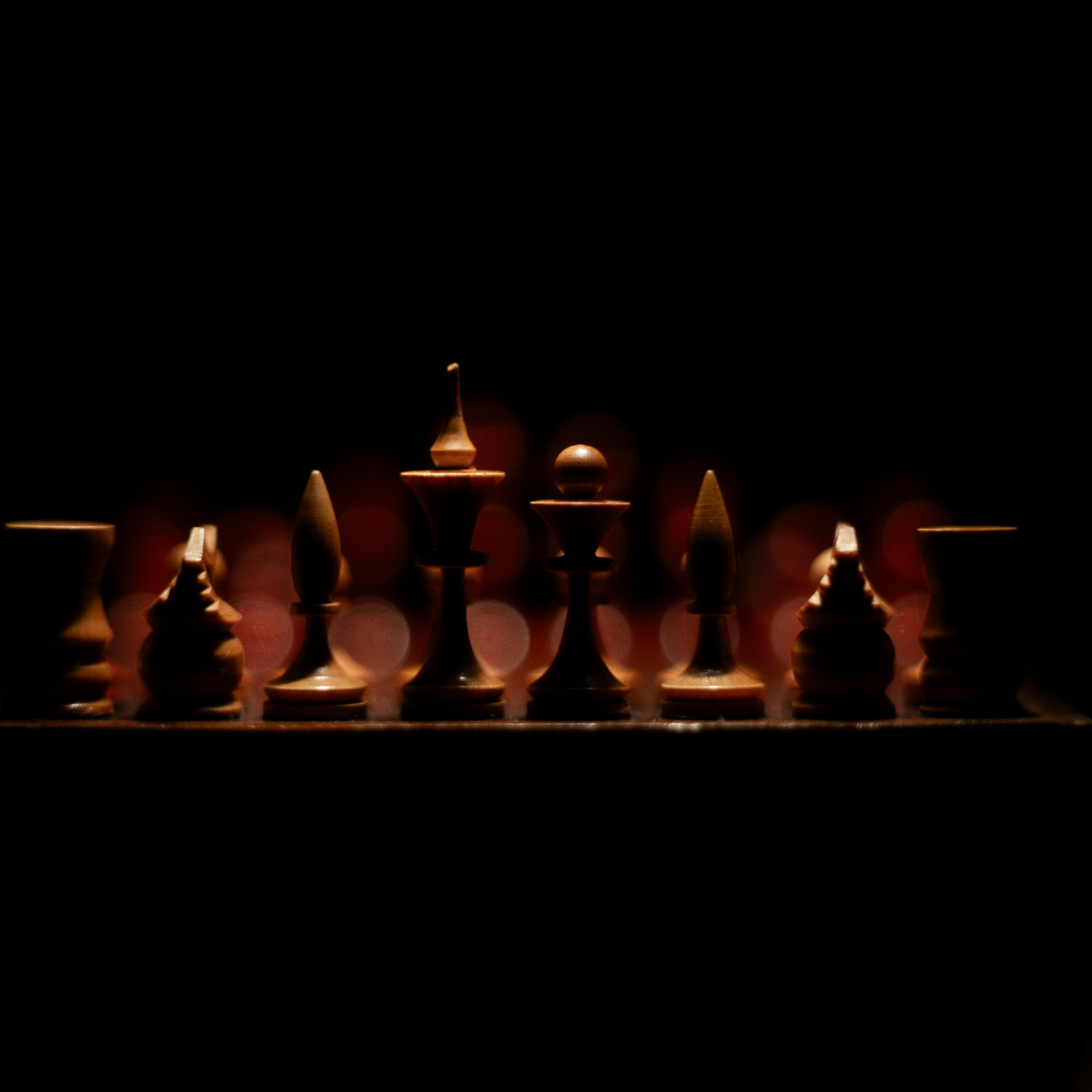 Chess pieces illuminated against a dark background.