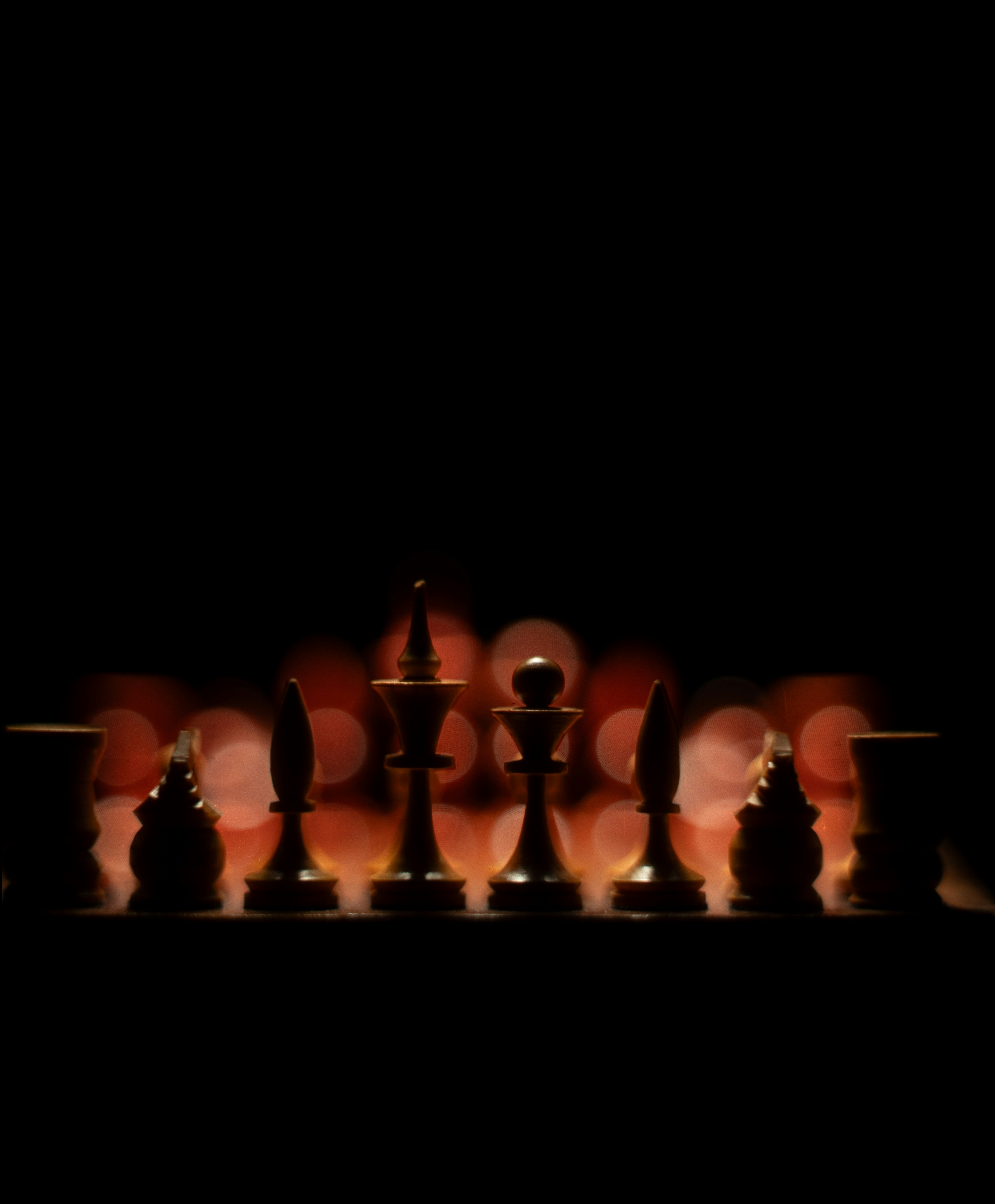 Silhouettes of chess pieces against bokeh lights