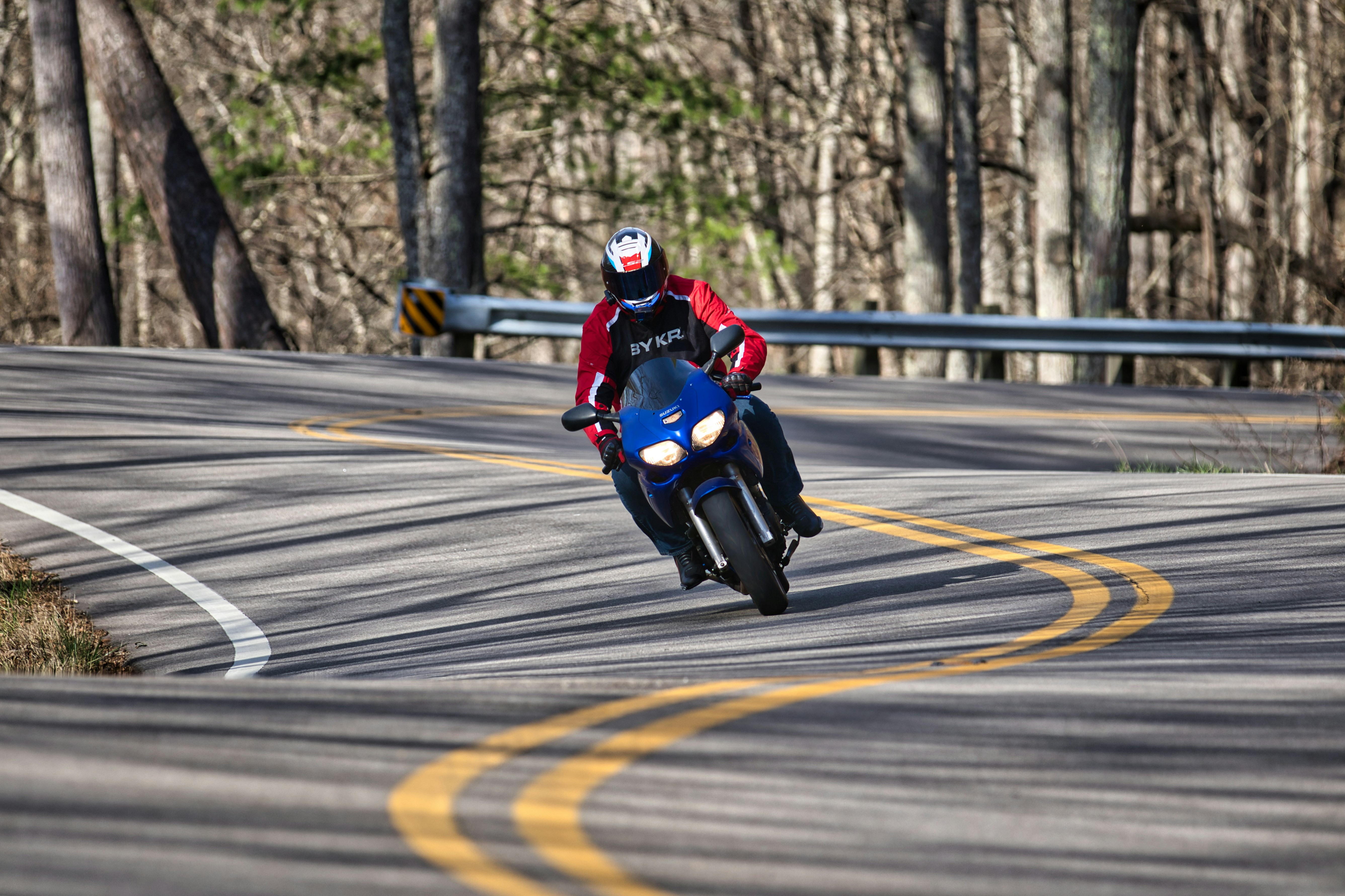 Motorcyclist on a winding road through trees