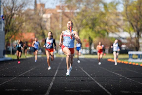 Female runners compete in a track and field race.
