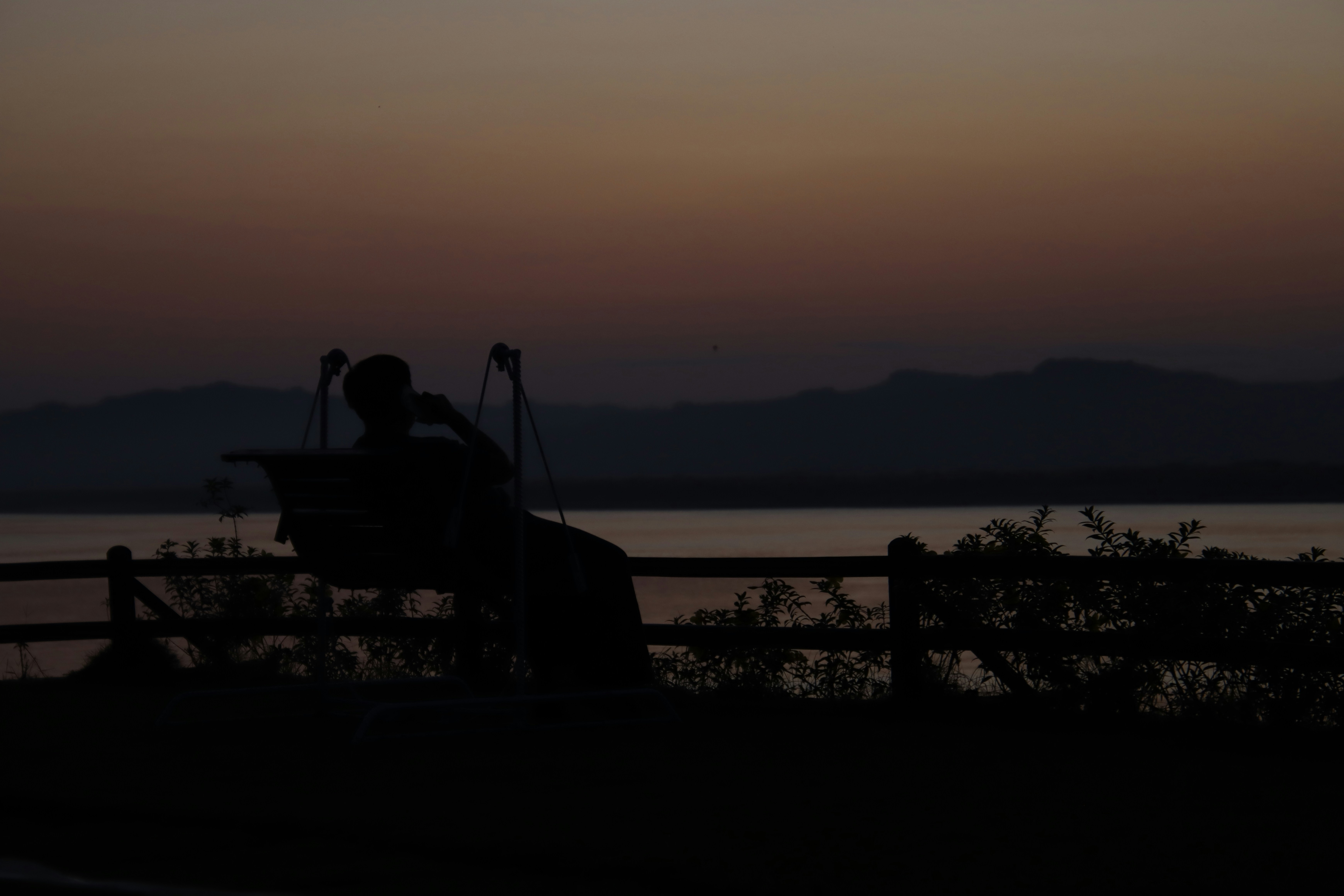 Silhouette of a person on a bench at dusk.