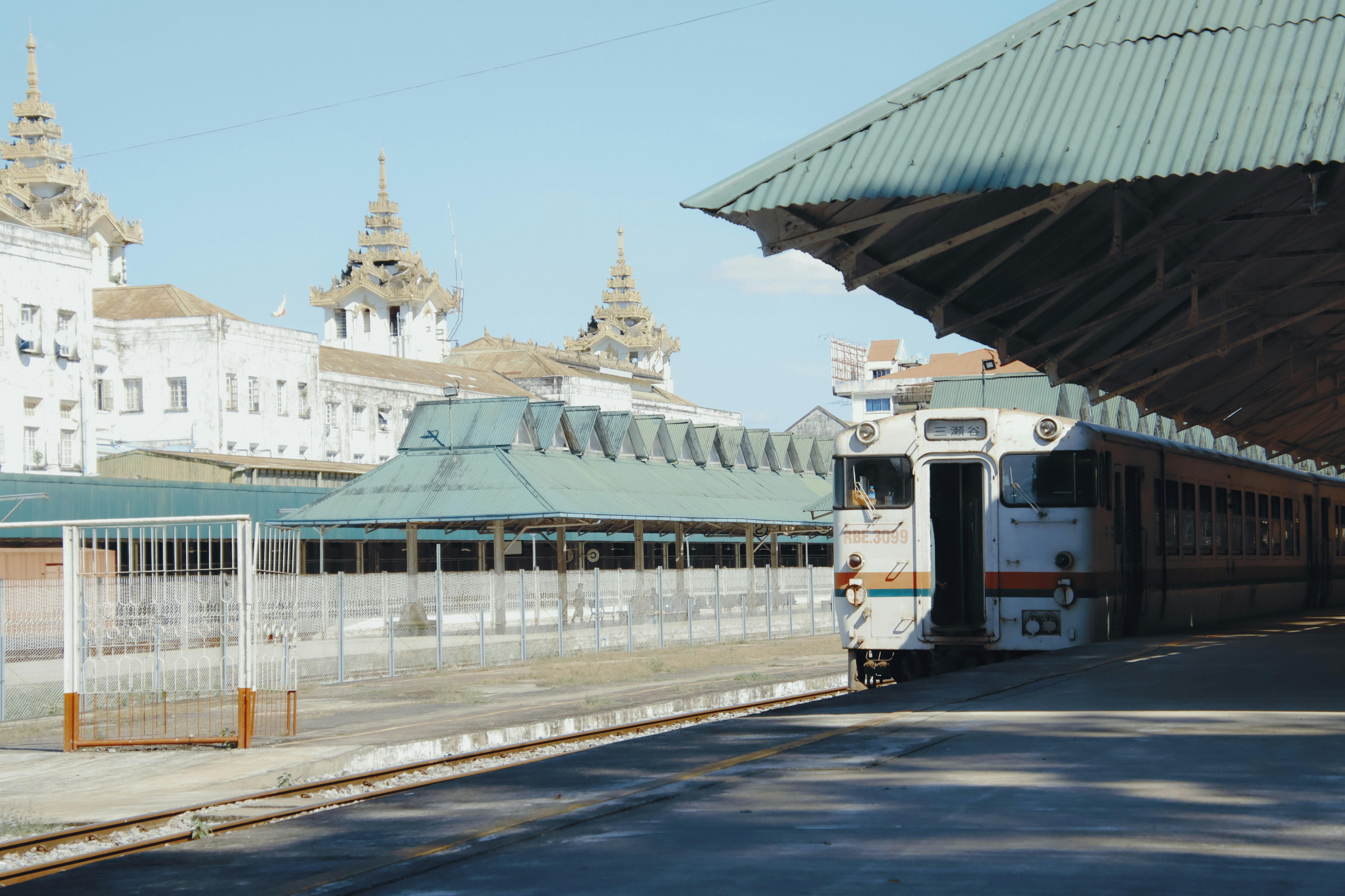 A train at a station with ornate buildings behind.
