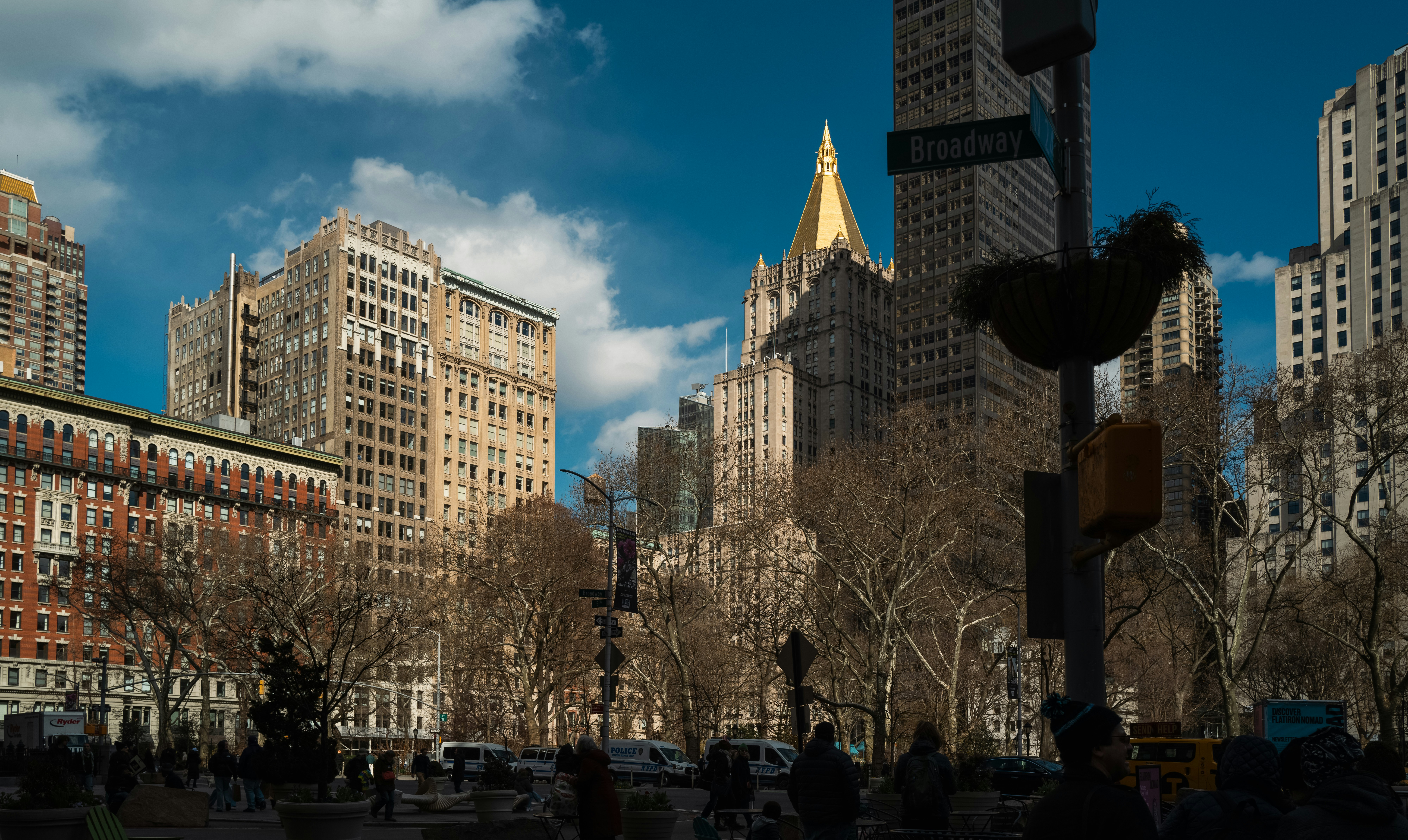 Cityscape with tall buildings and trees under blue sky