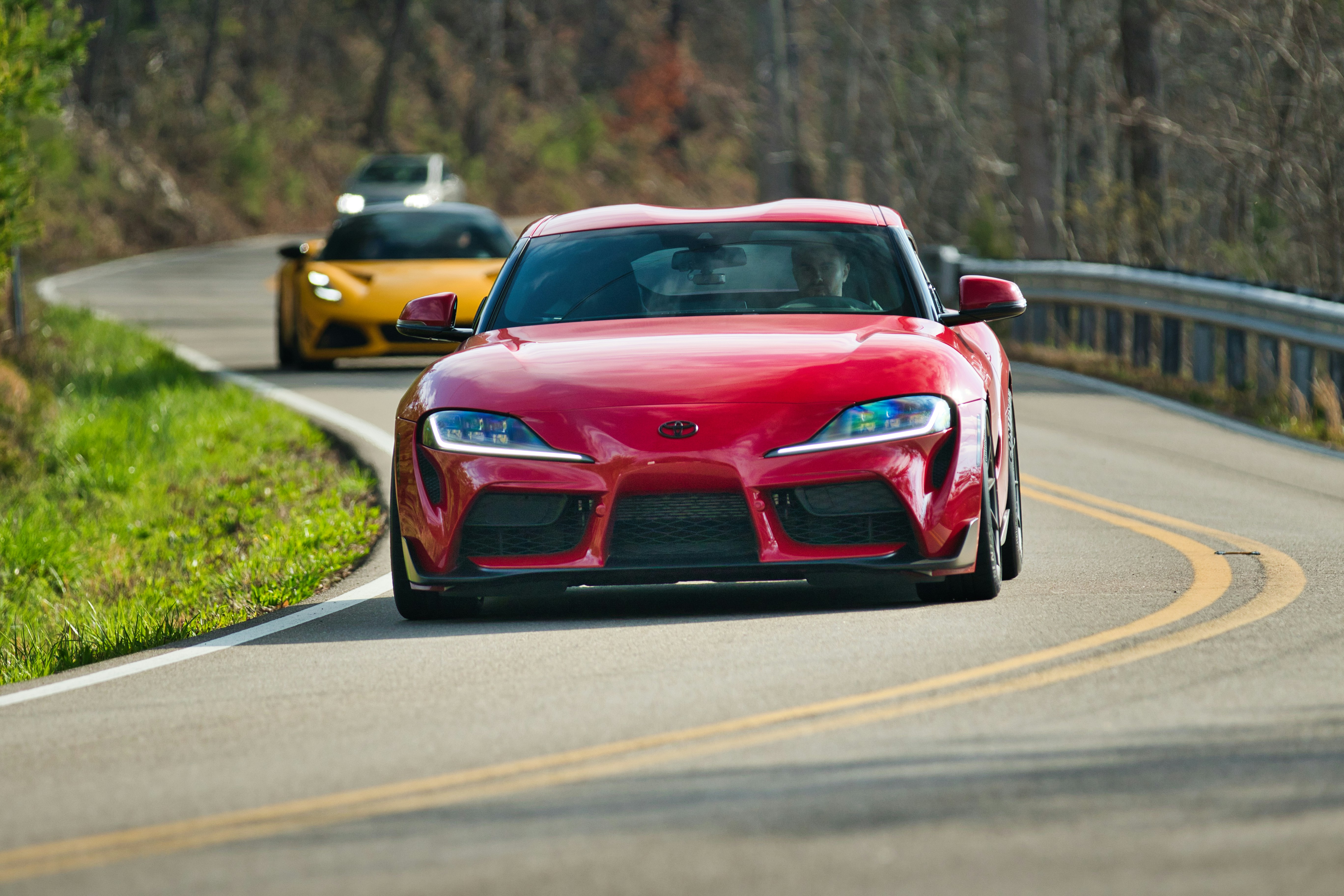 A red sports car drives on a winding road