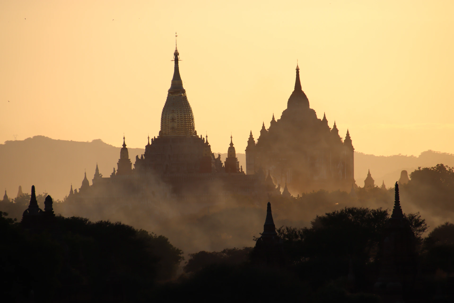 Ancient temples silhouetted against a hazy sunrise sky.