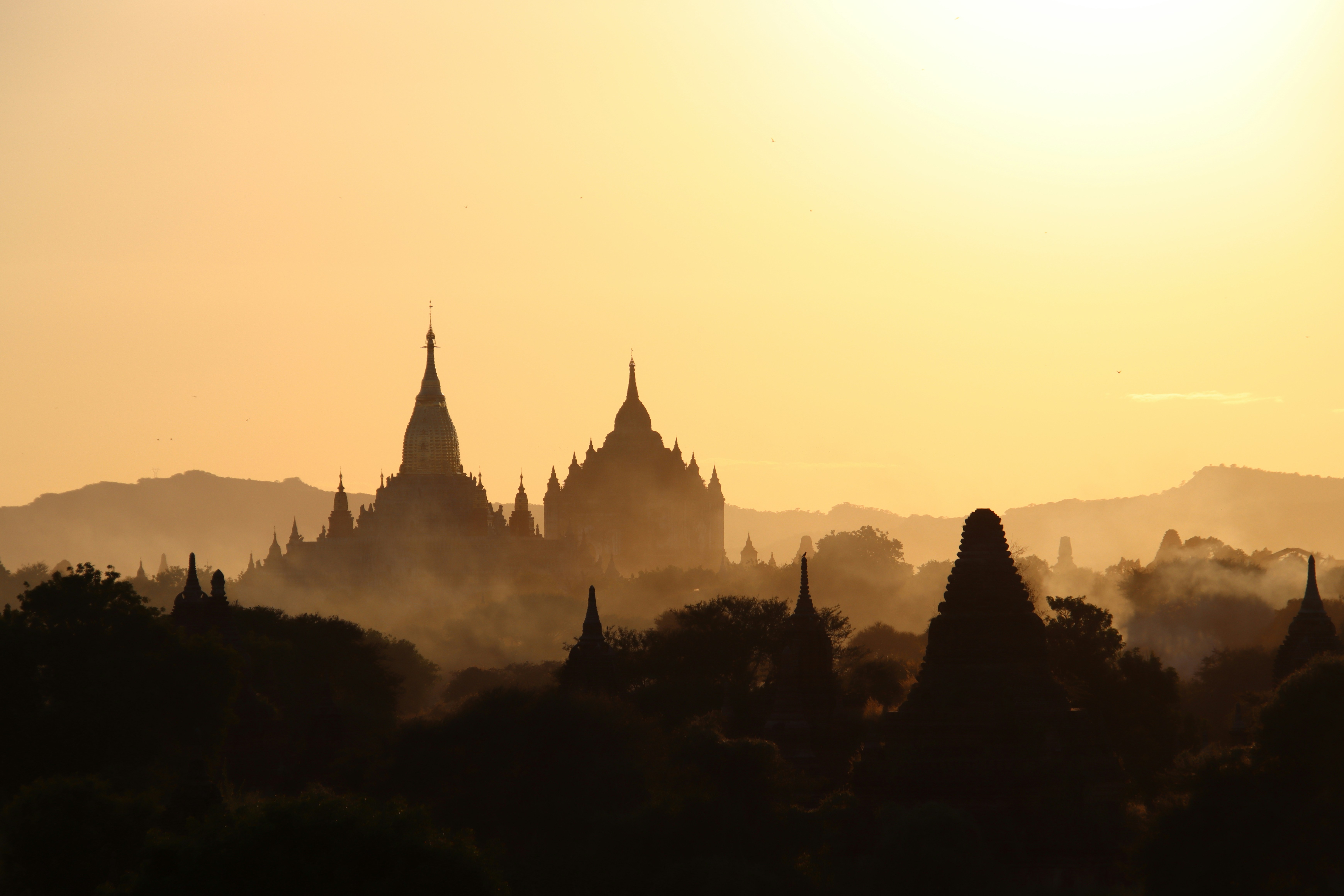 Ancient temples silhouetted against a hazy sunrise sky.