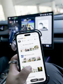 Person holding smartphone with car dashboard screen