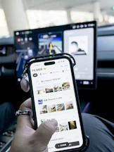 Person holding smartphone with car dashboard screen