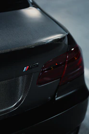 Close-up of a black car's rear with carbon fiber accents.