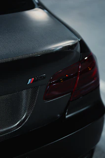 Close-up of a black car's rear with carbon fiber accents.