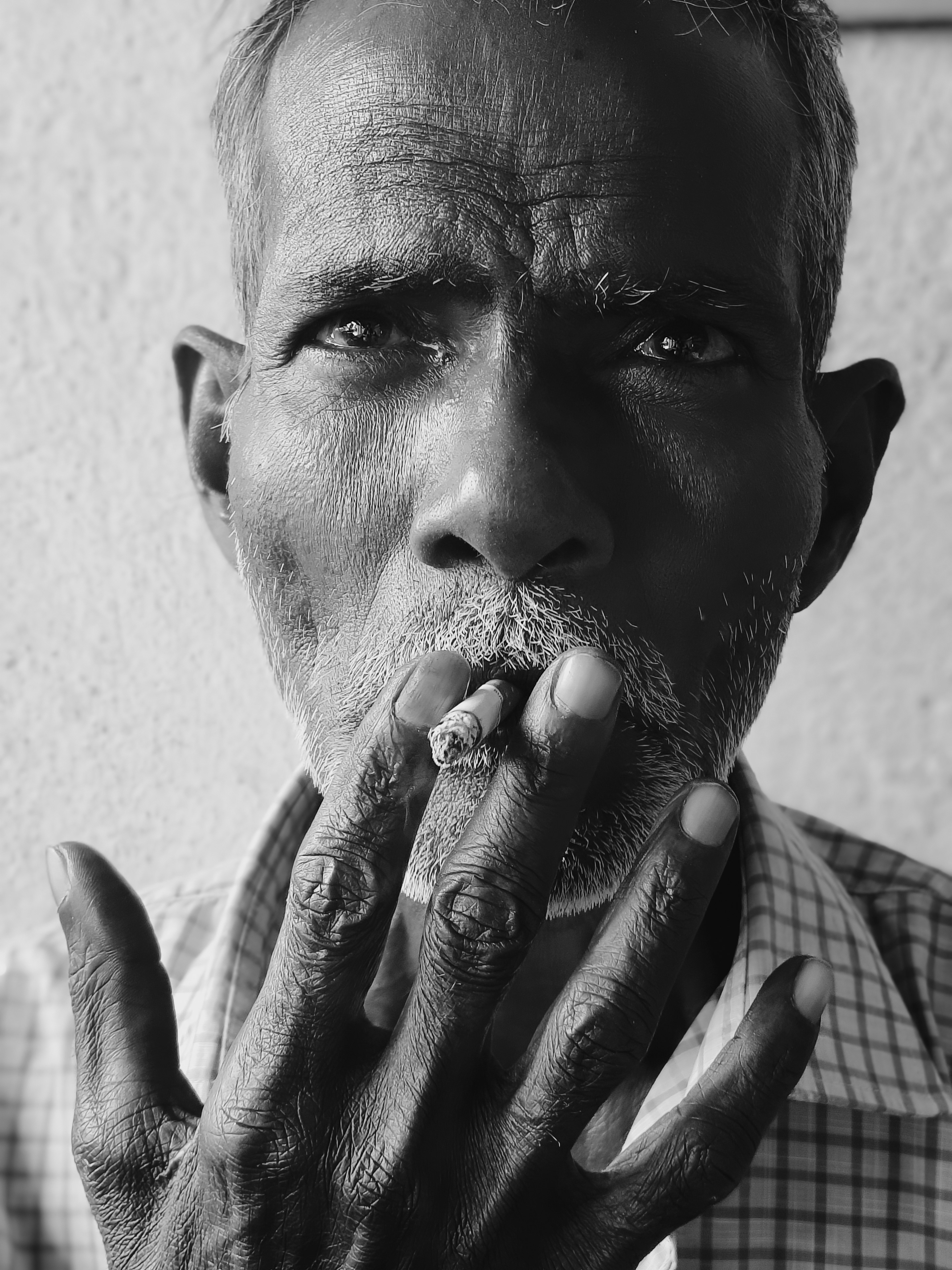 Un homme âgé fumant une cigarette avec des mains usées.