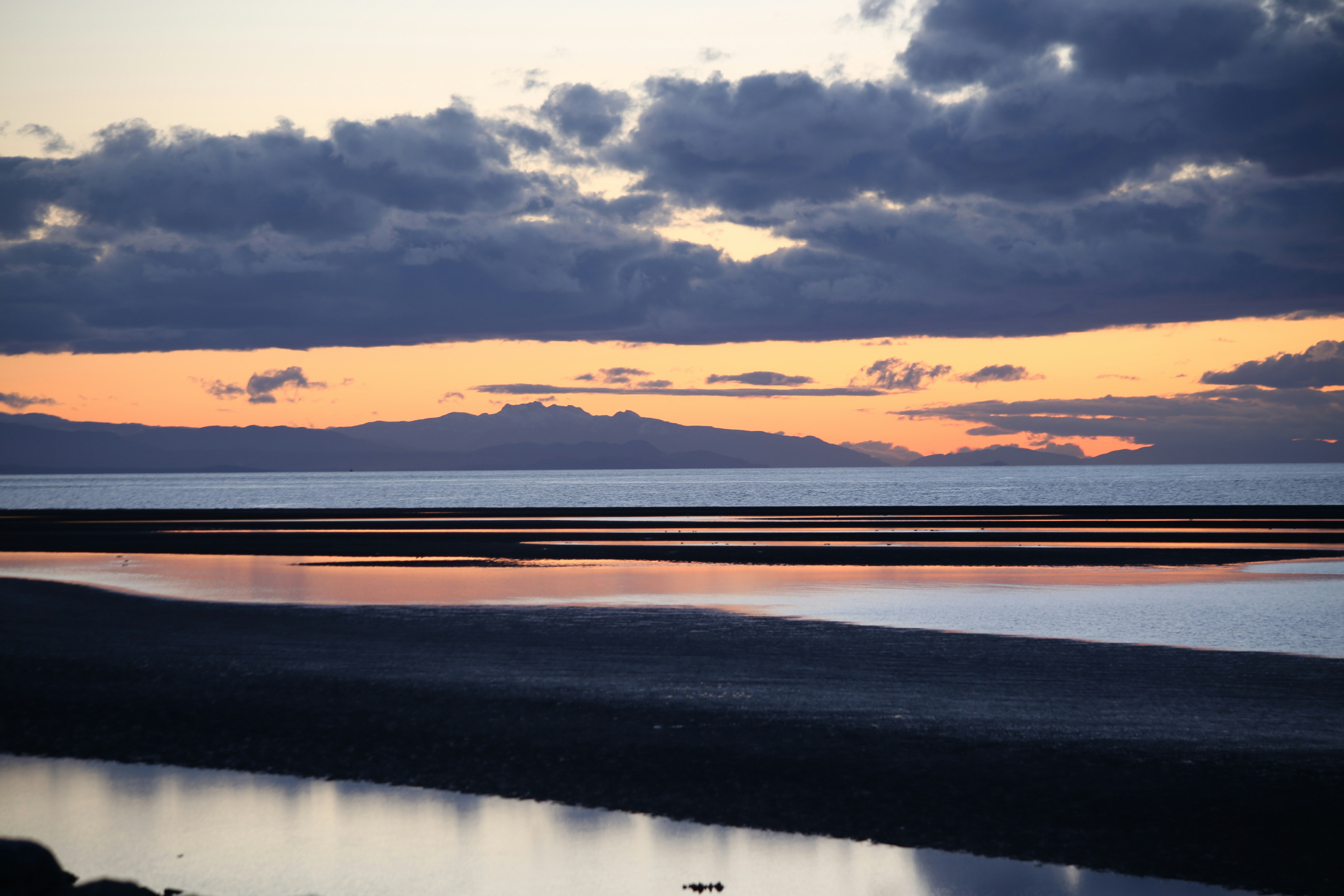 Sunset over a calm ocean with distant mountains