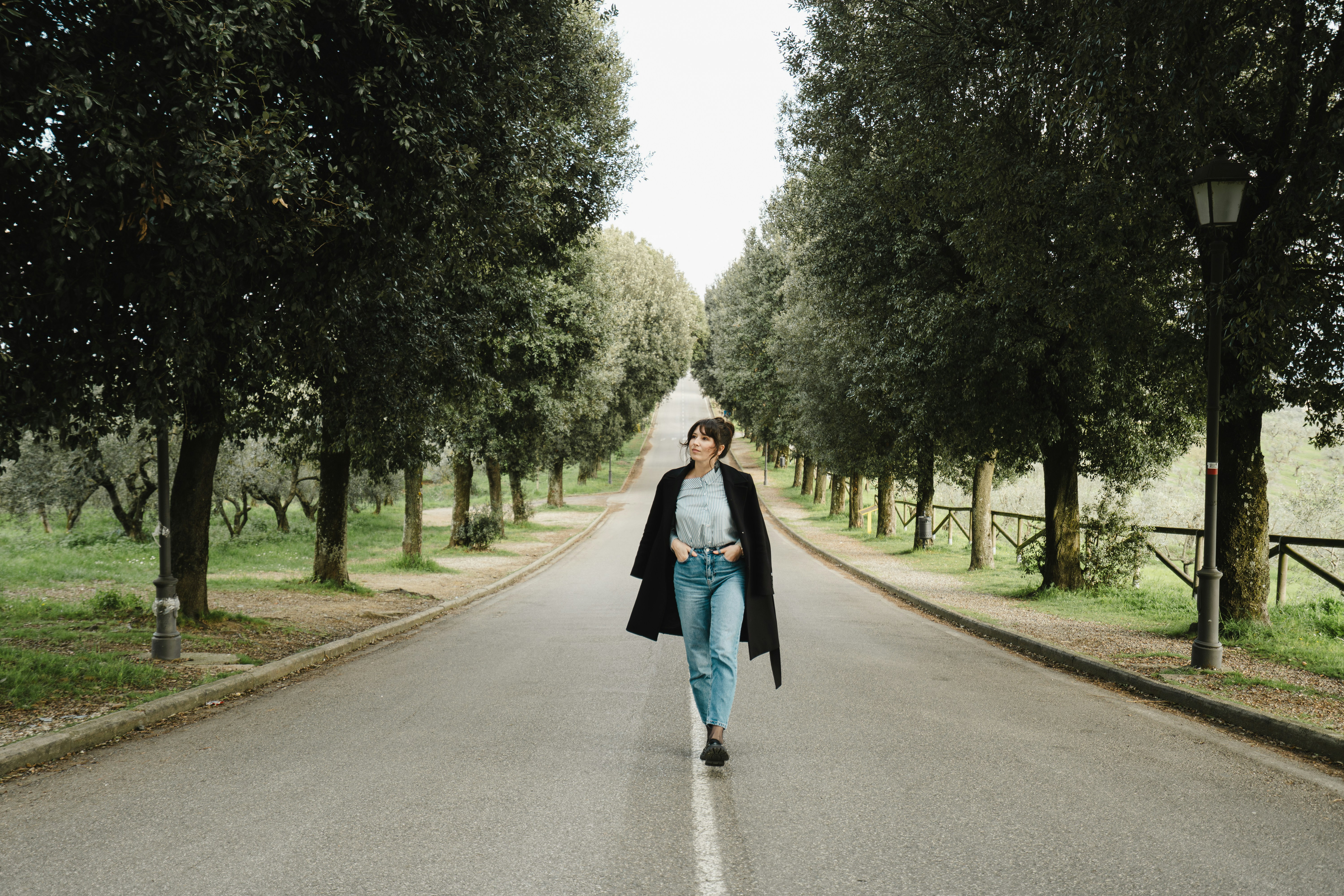 Woman walking down a tree-lined road