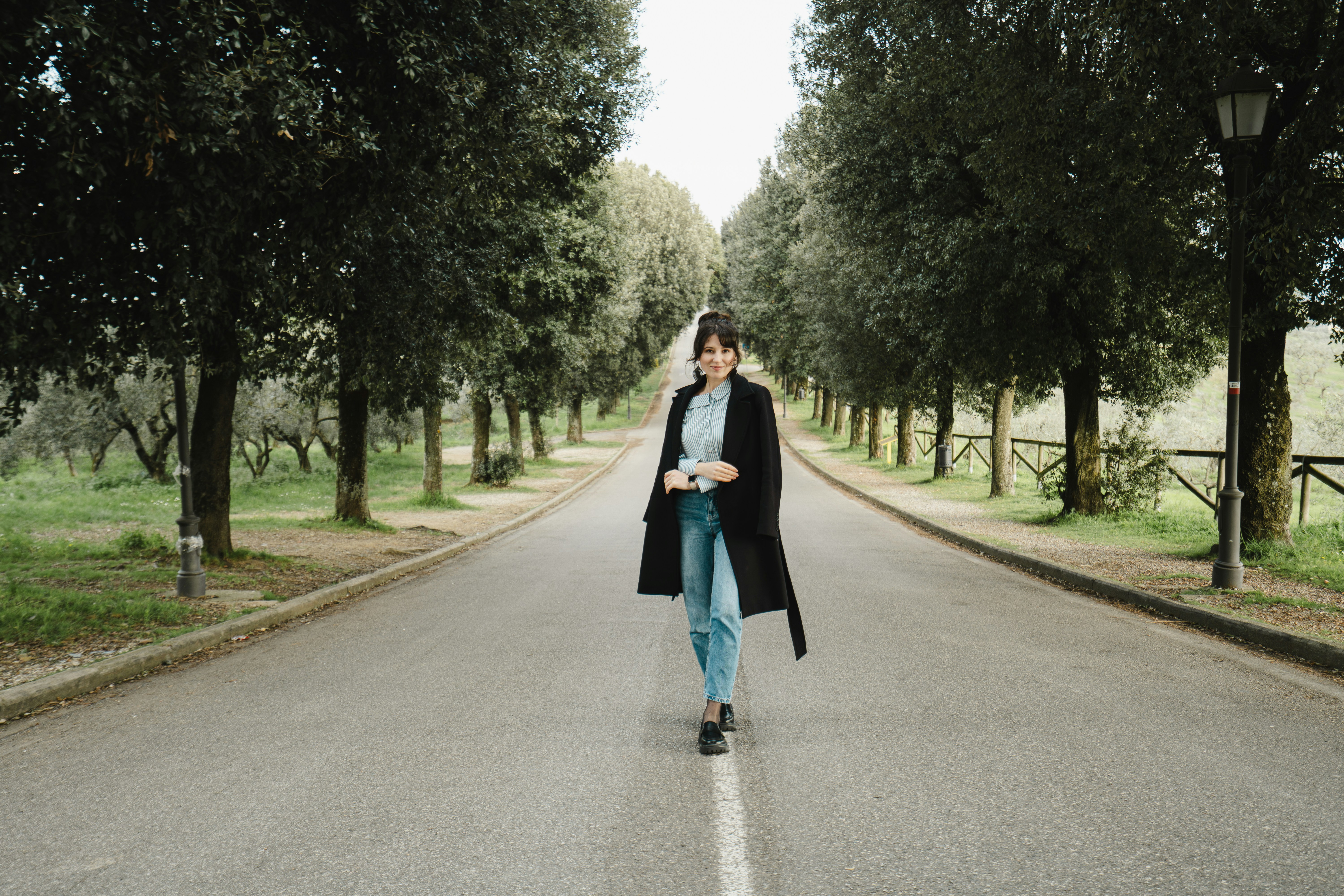 Woman walking down tree-lined road