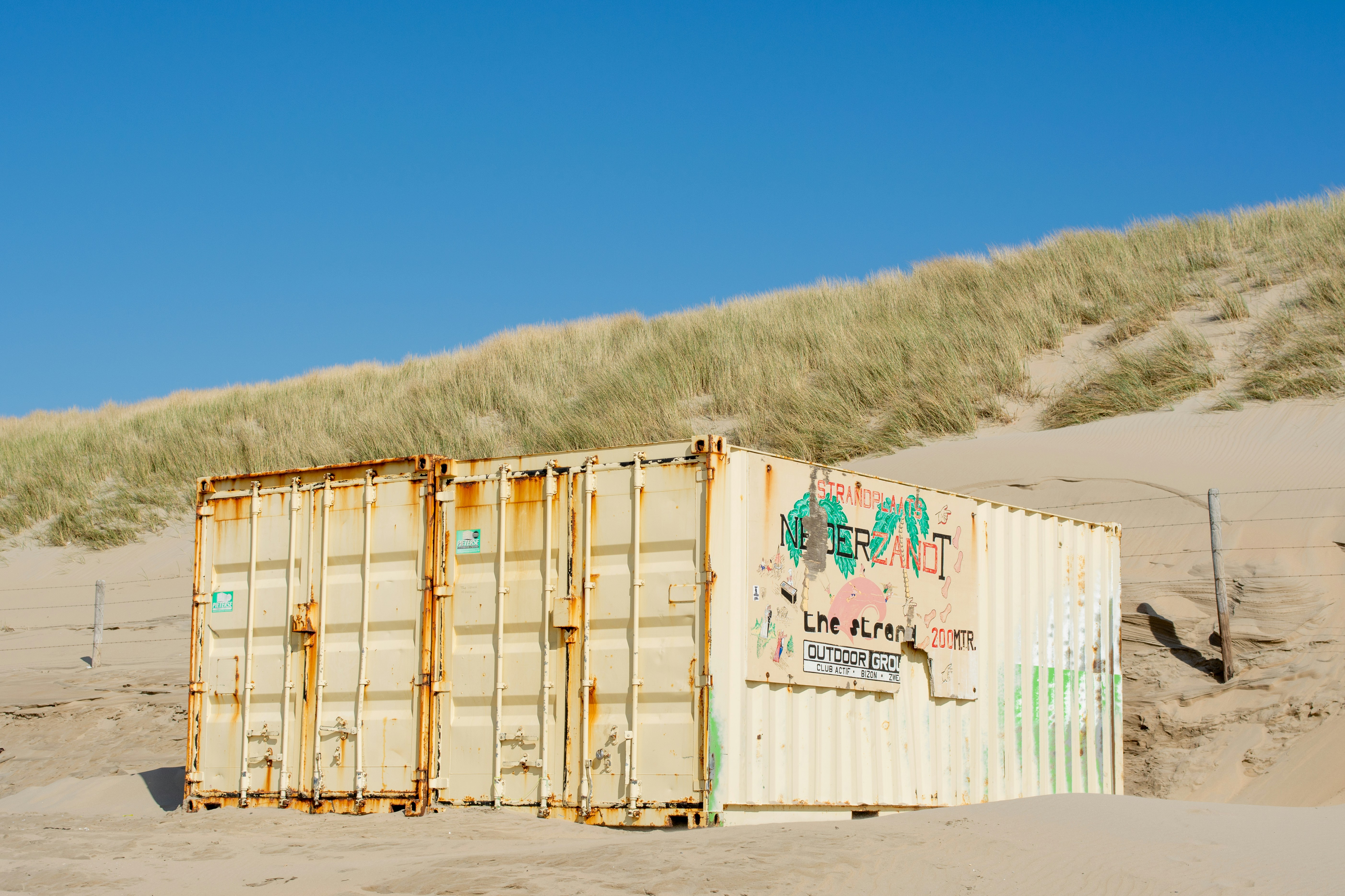Contenedor de transporte desgastado en una duna de arena