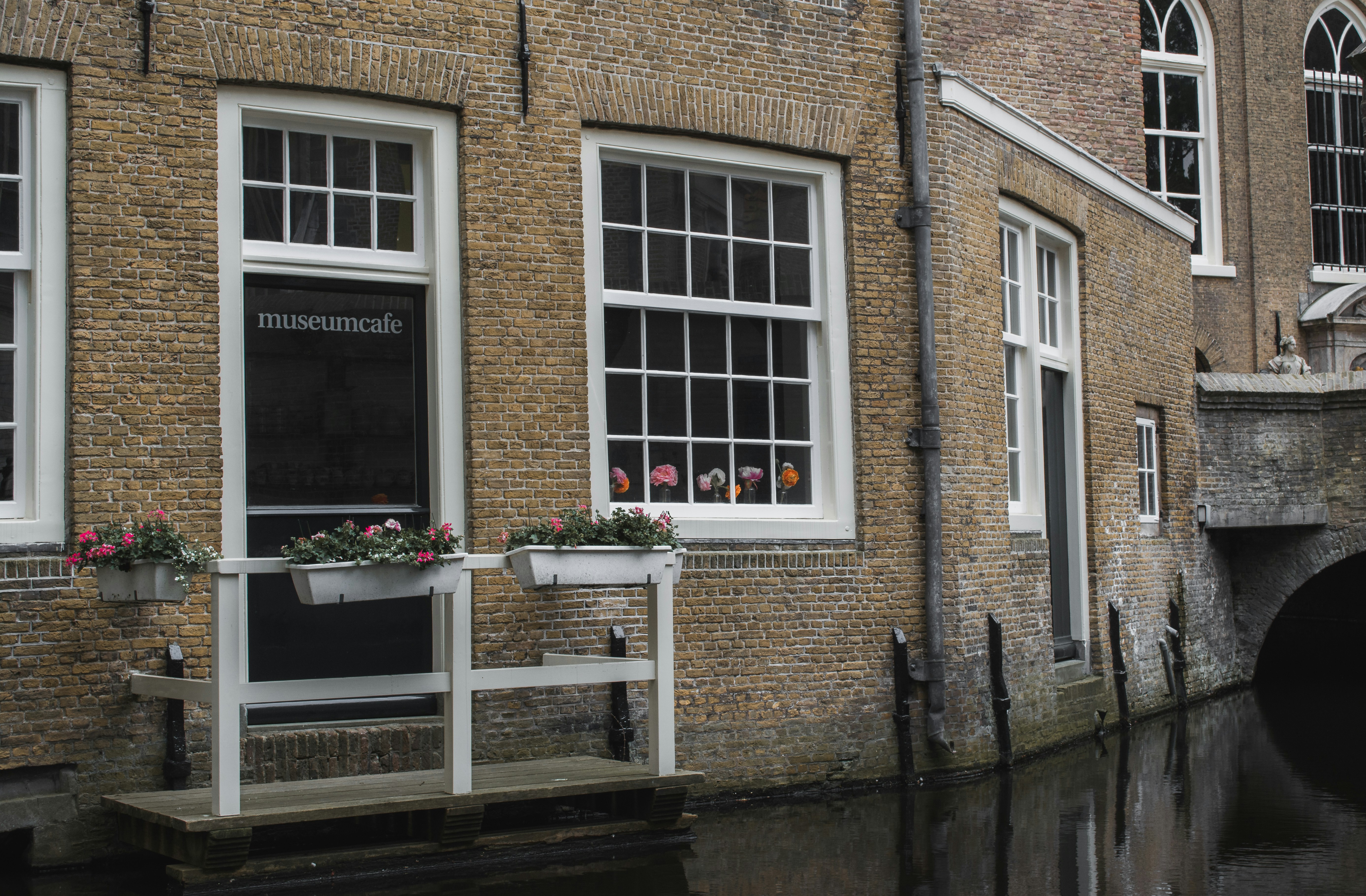 Edificio de ladrillo con ventanas y flores junto al canal.