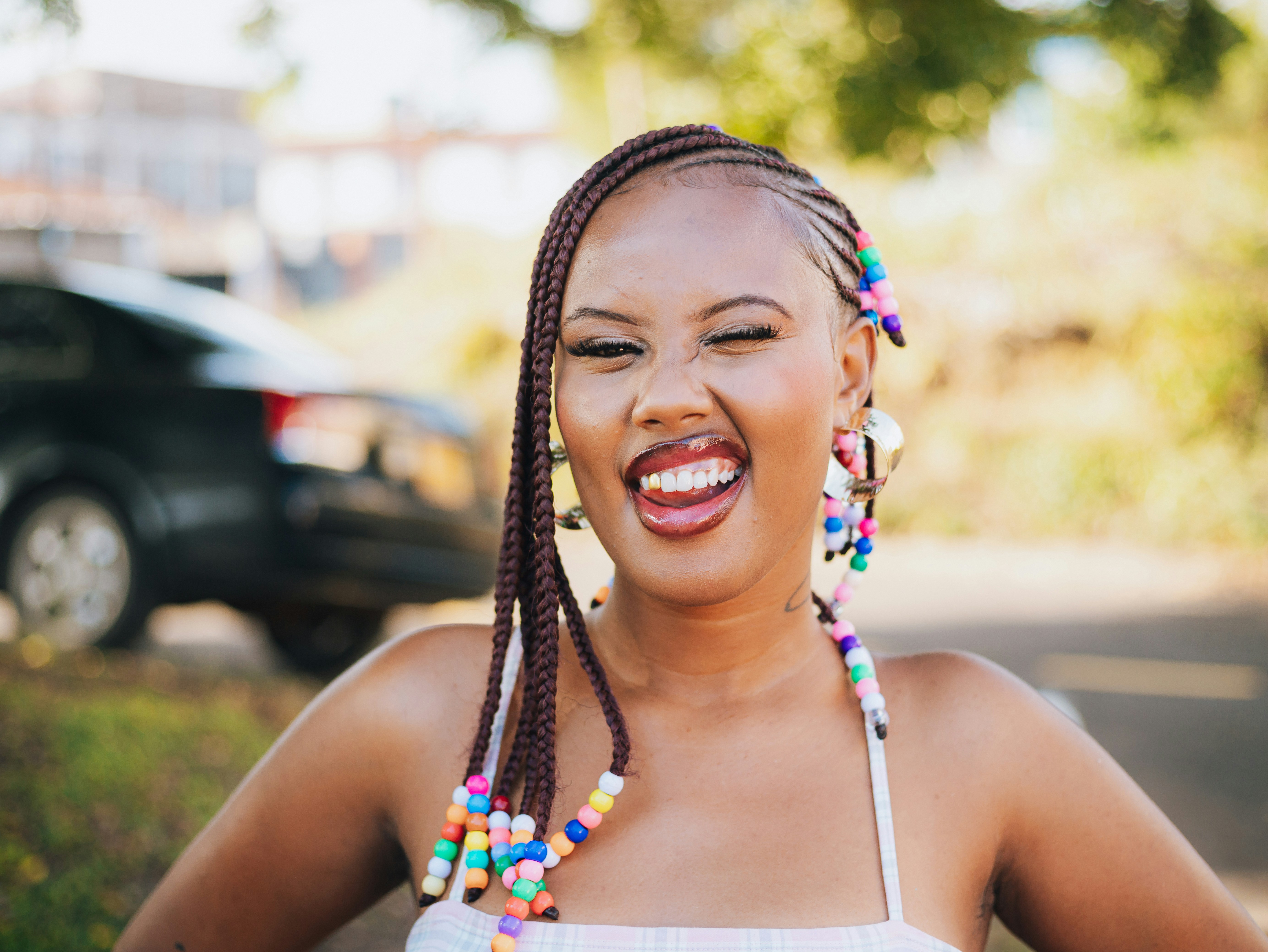 Young woman with braided hair and colorful beads laughing