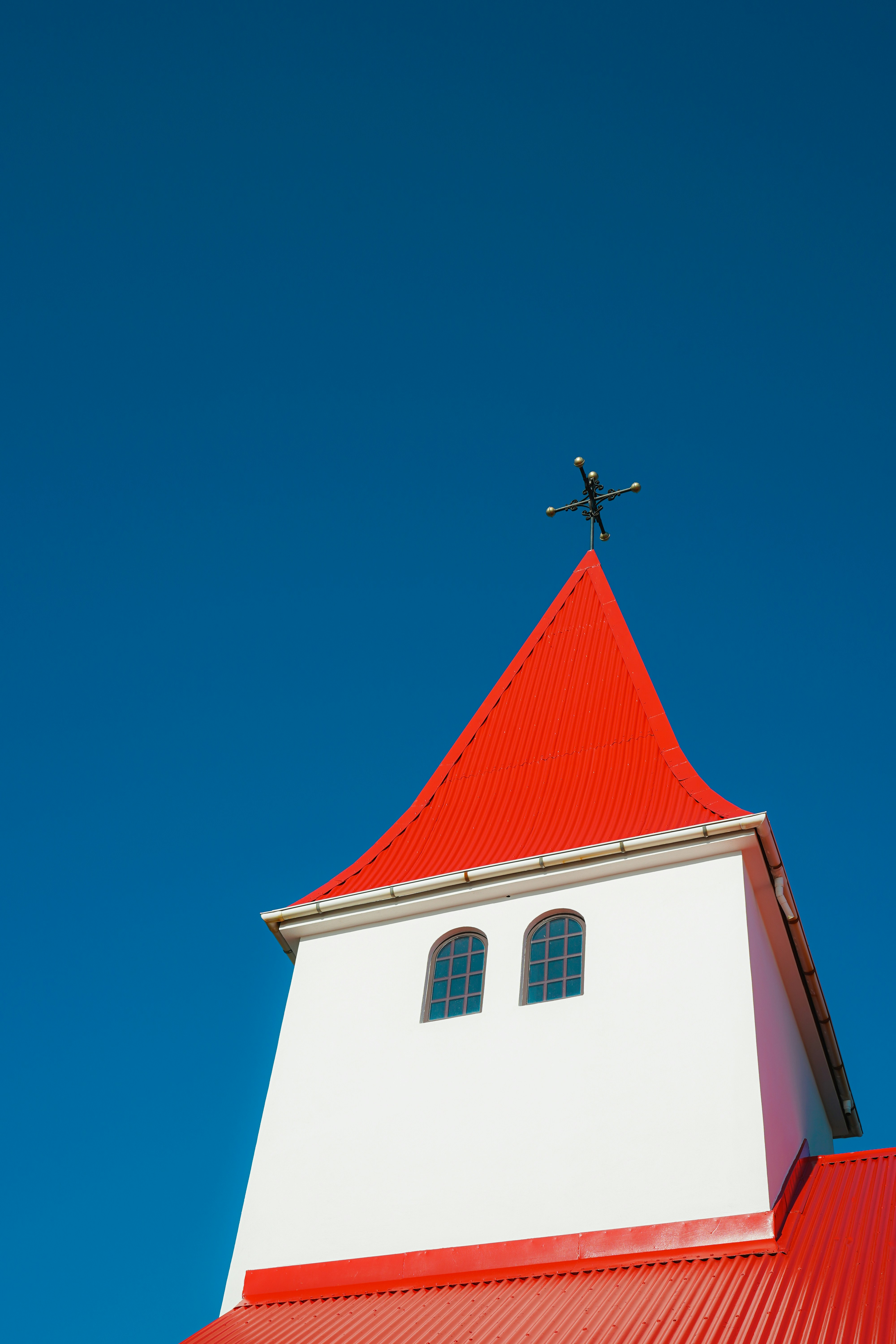 White church tower with red roof against blue sky