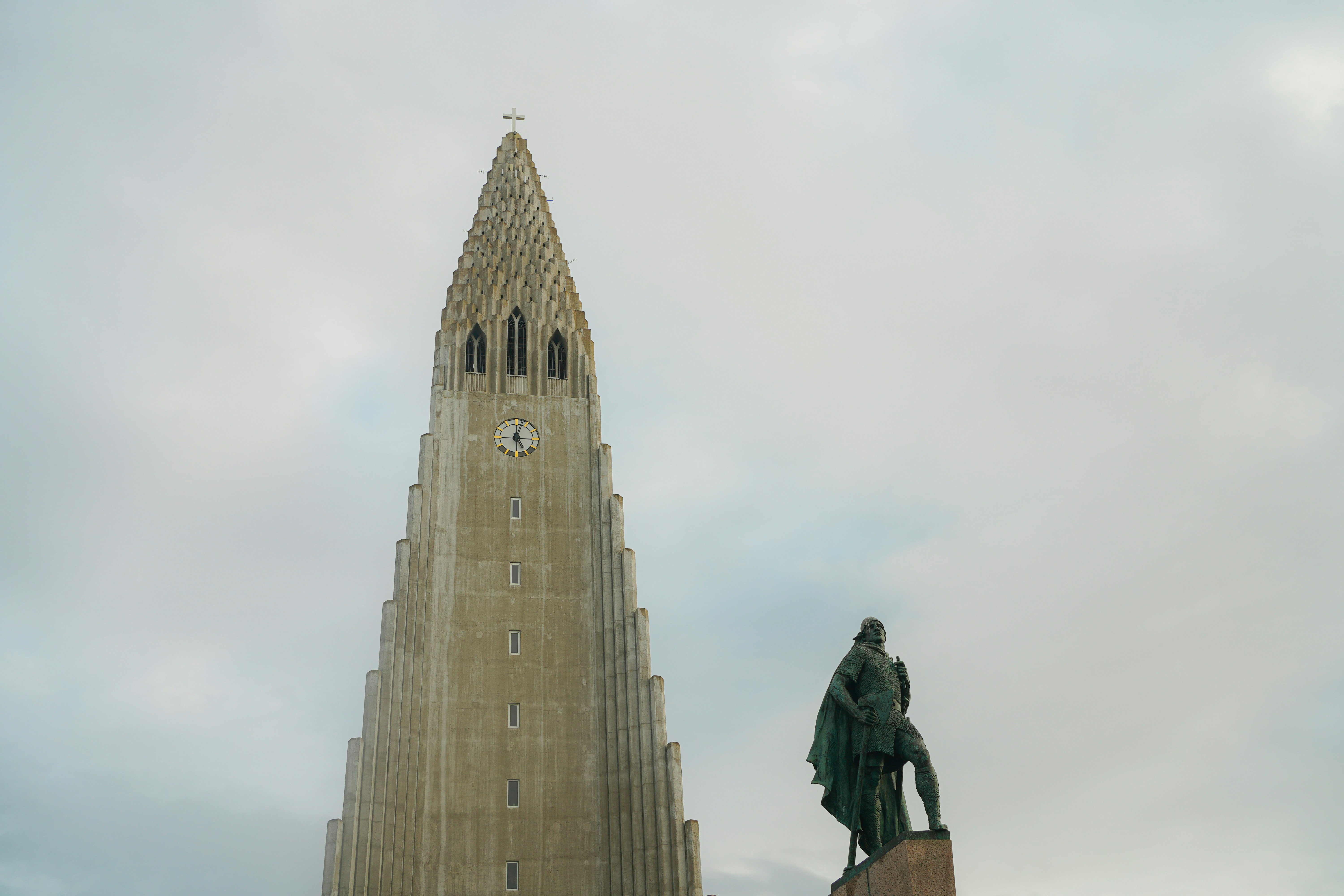 Tall tower and statue against a cloudy sky
