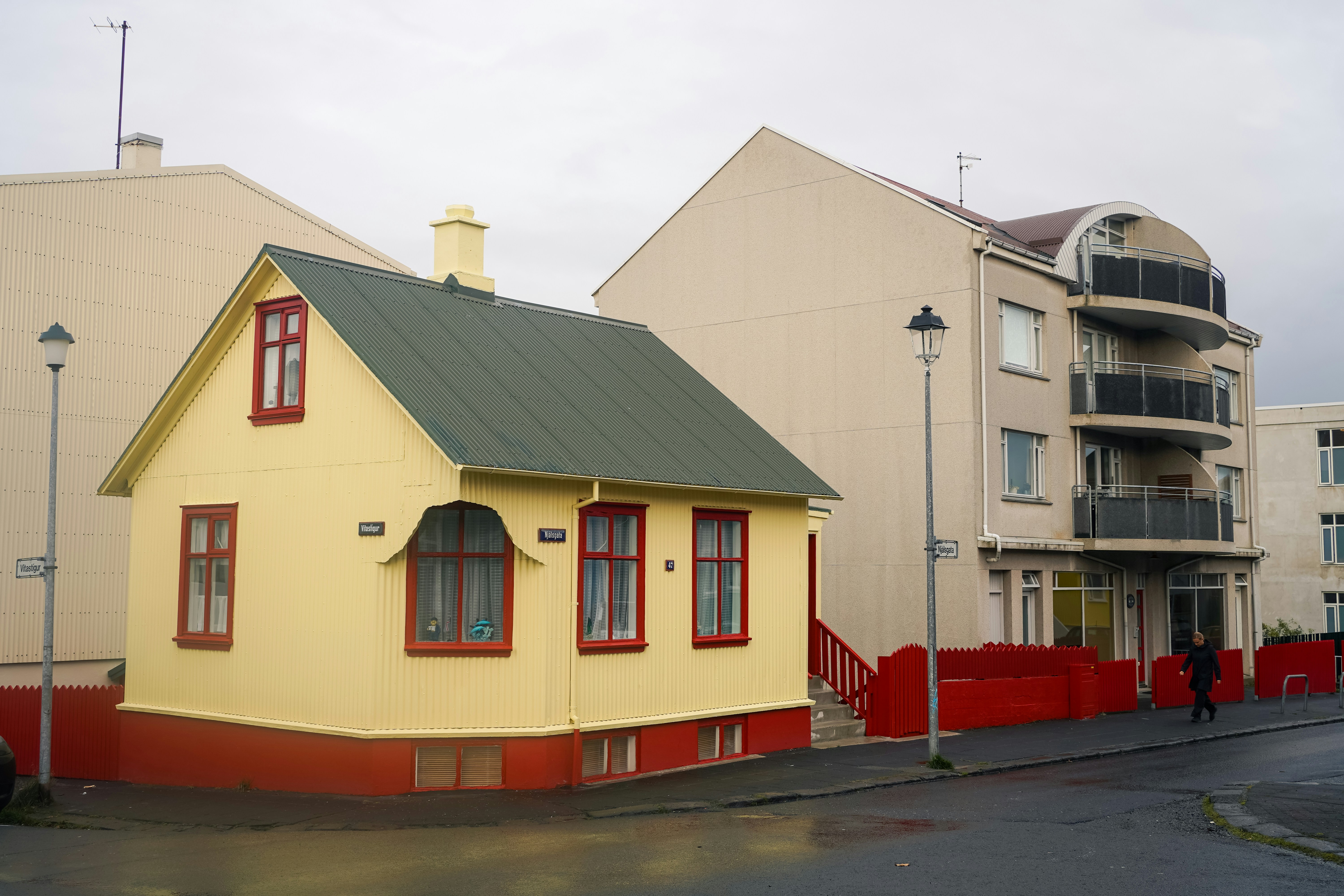 A small yellow house next to a larger building.