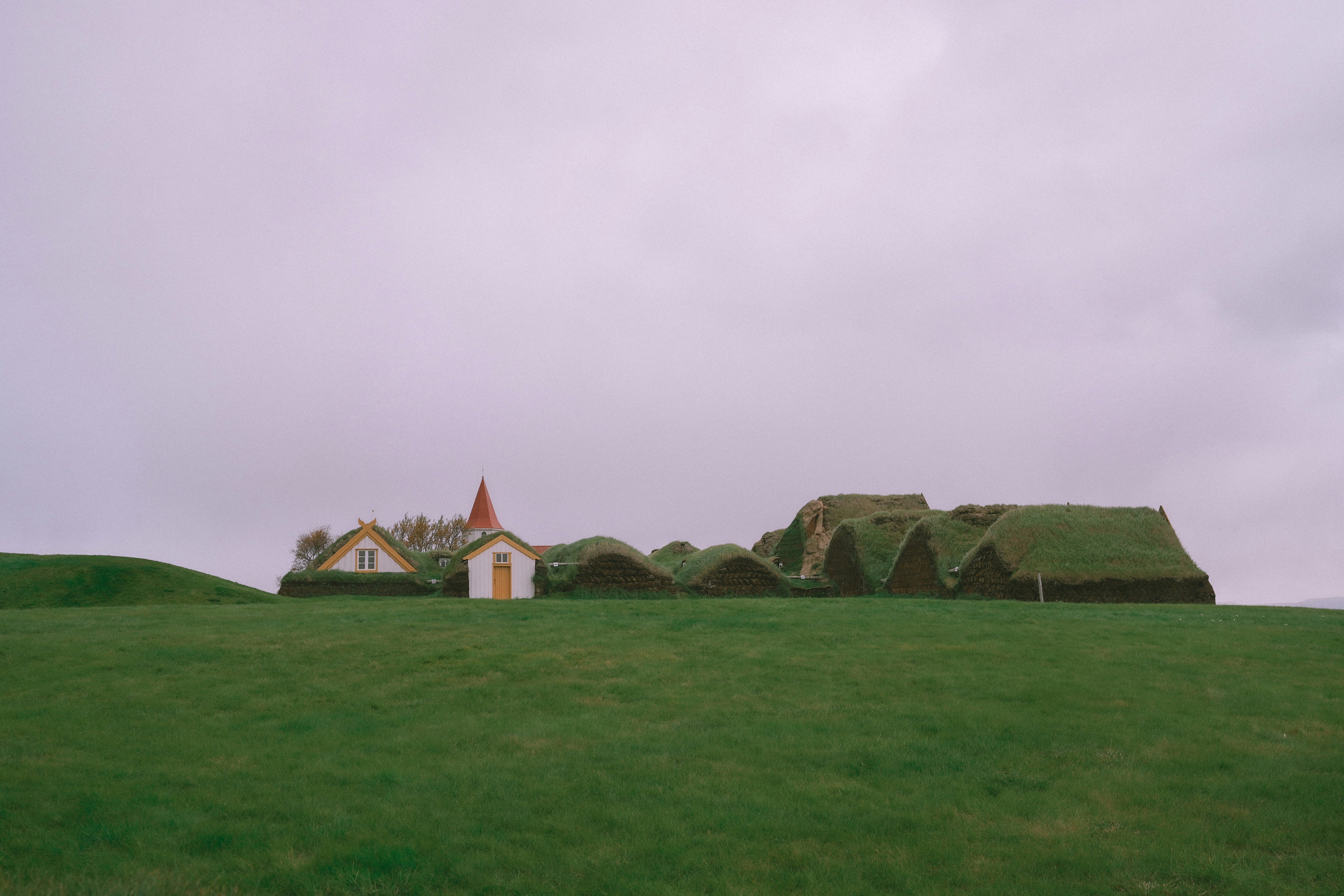 Grass-roofed buildings under a cloudy sky.