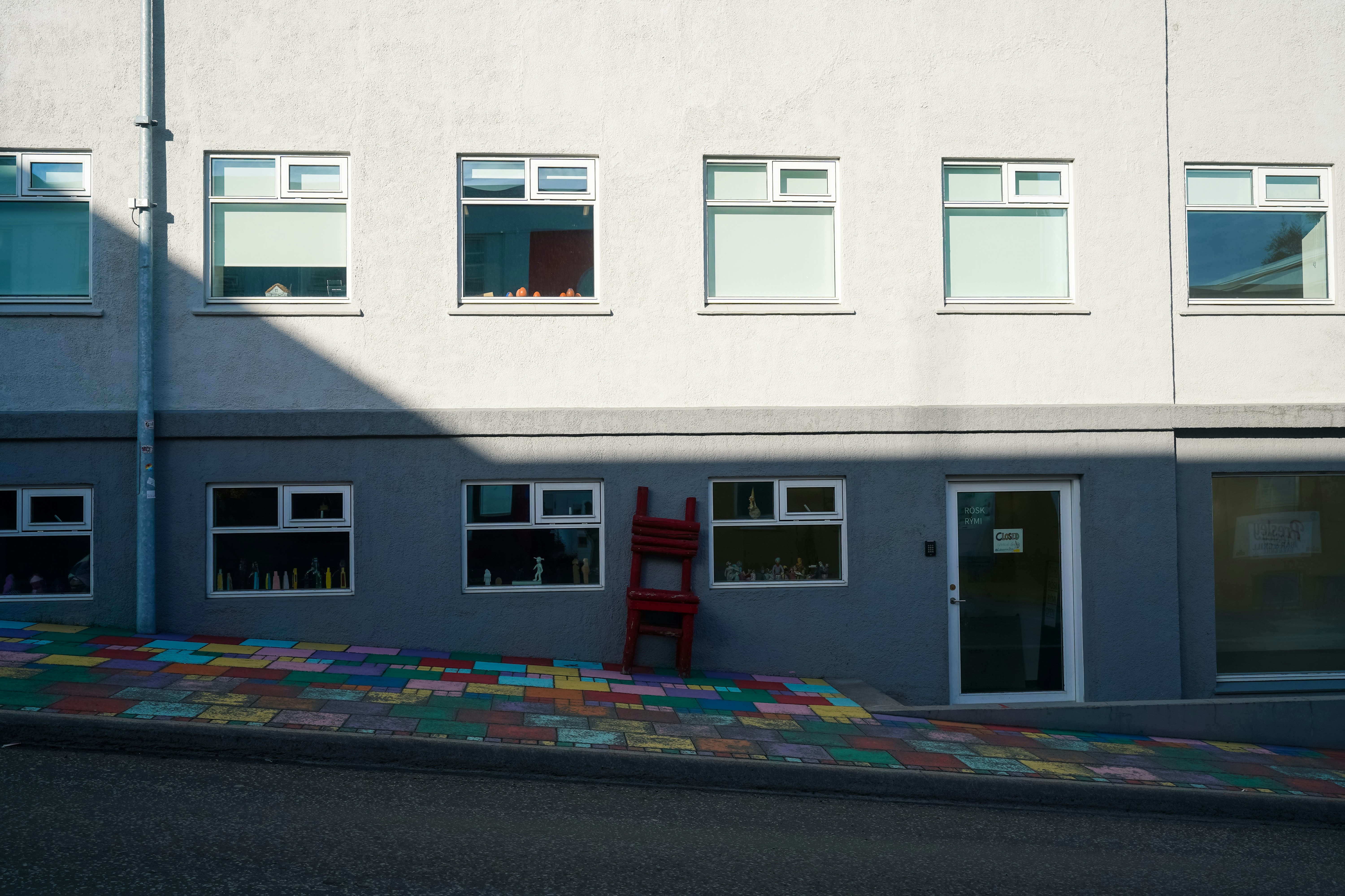 Red chair against a building with colorful pavement