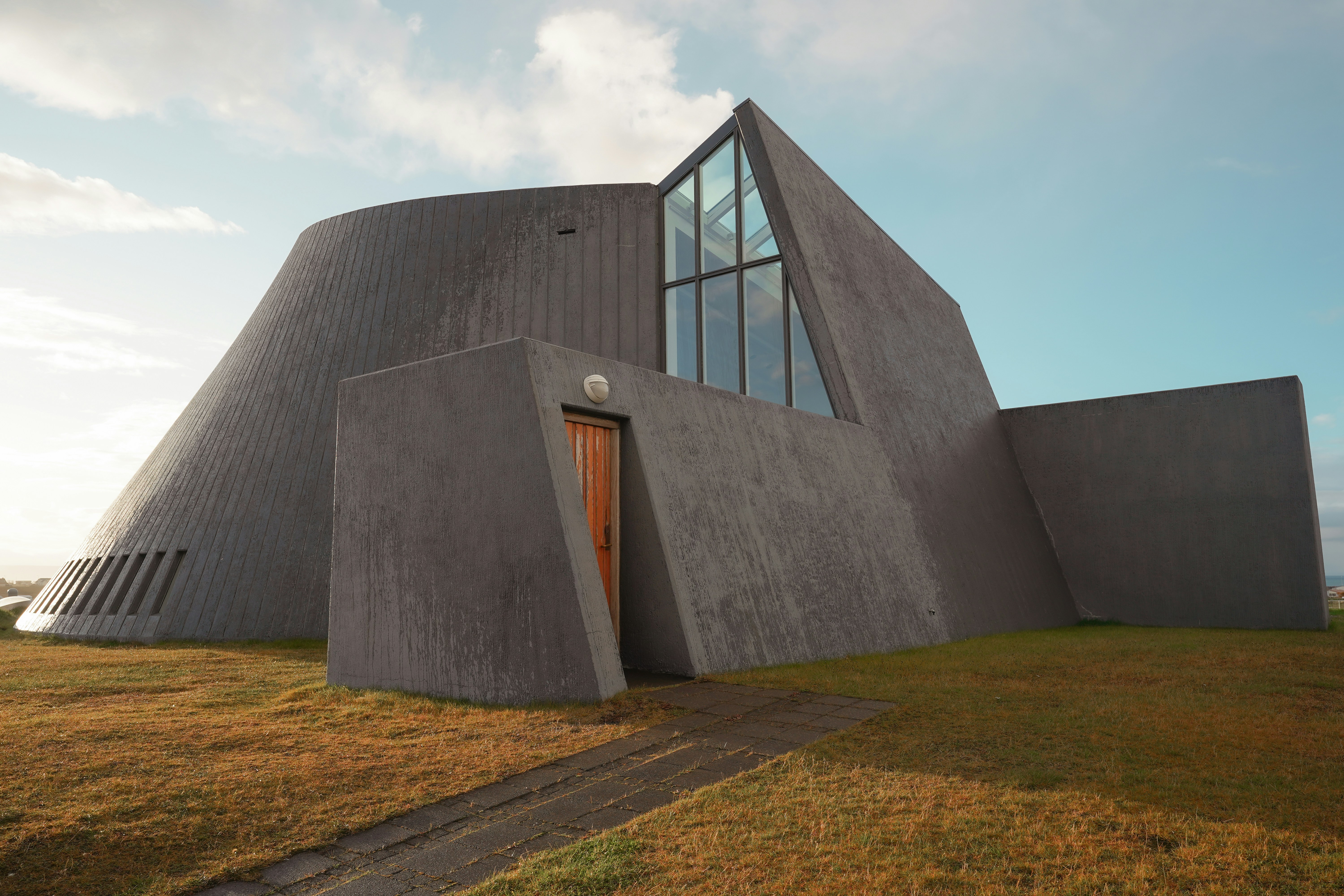Modern concrete building with wooden door under sky