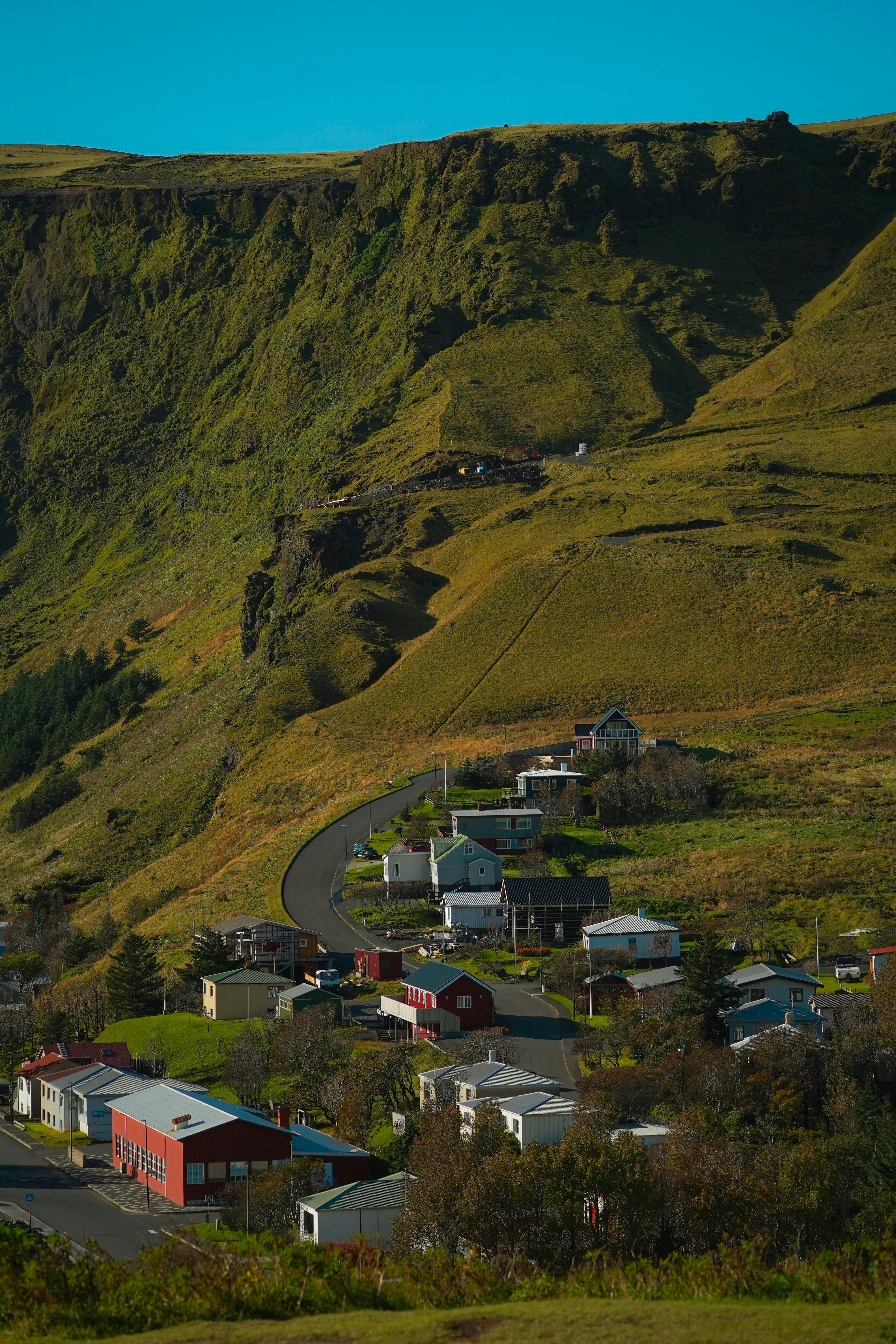 Small village nestled at the base of a green mountain.