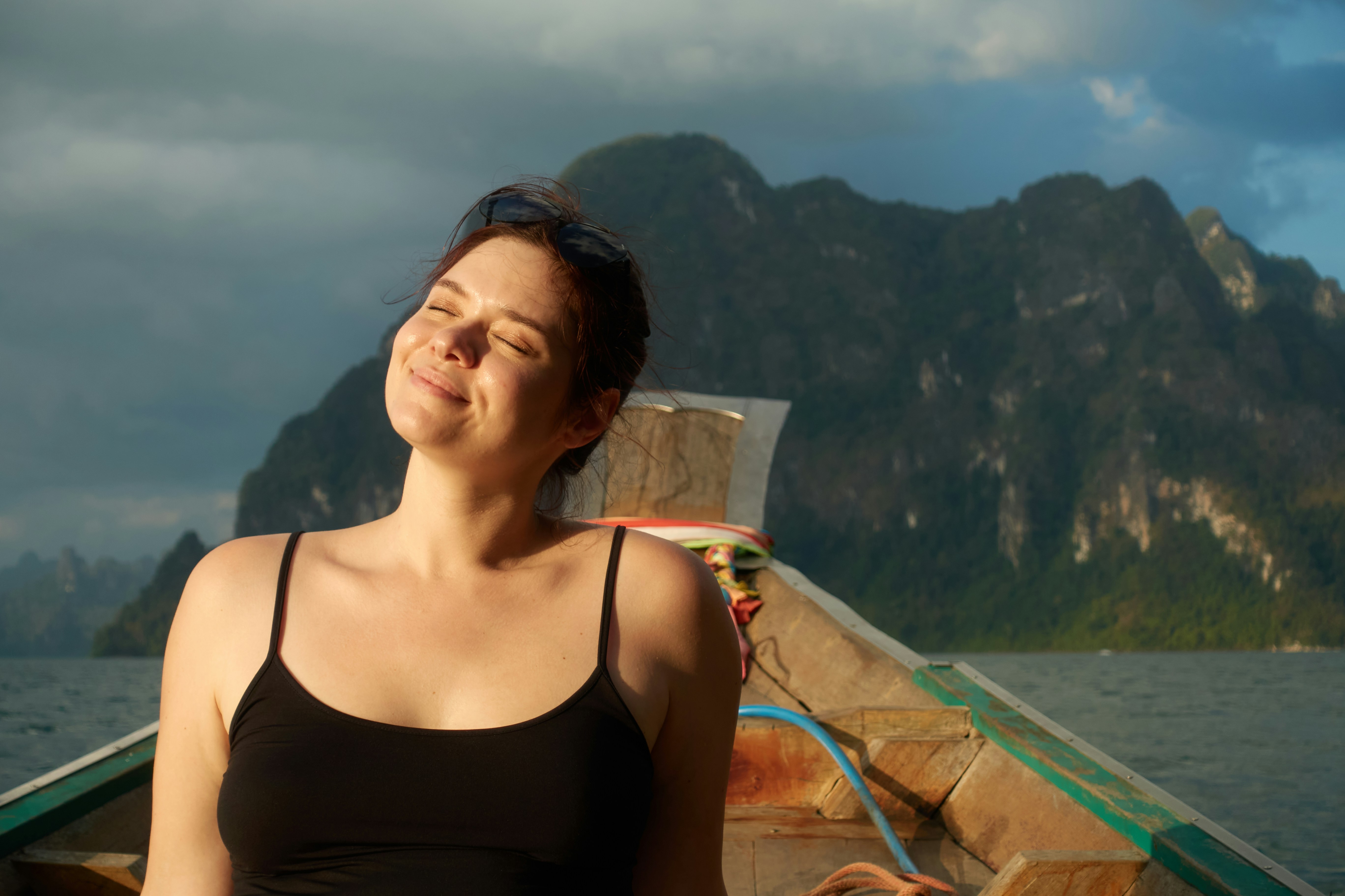 Femme profitant du soleil sur un bateau avec des montagnes