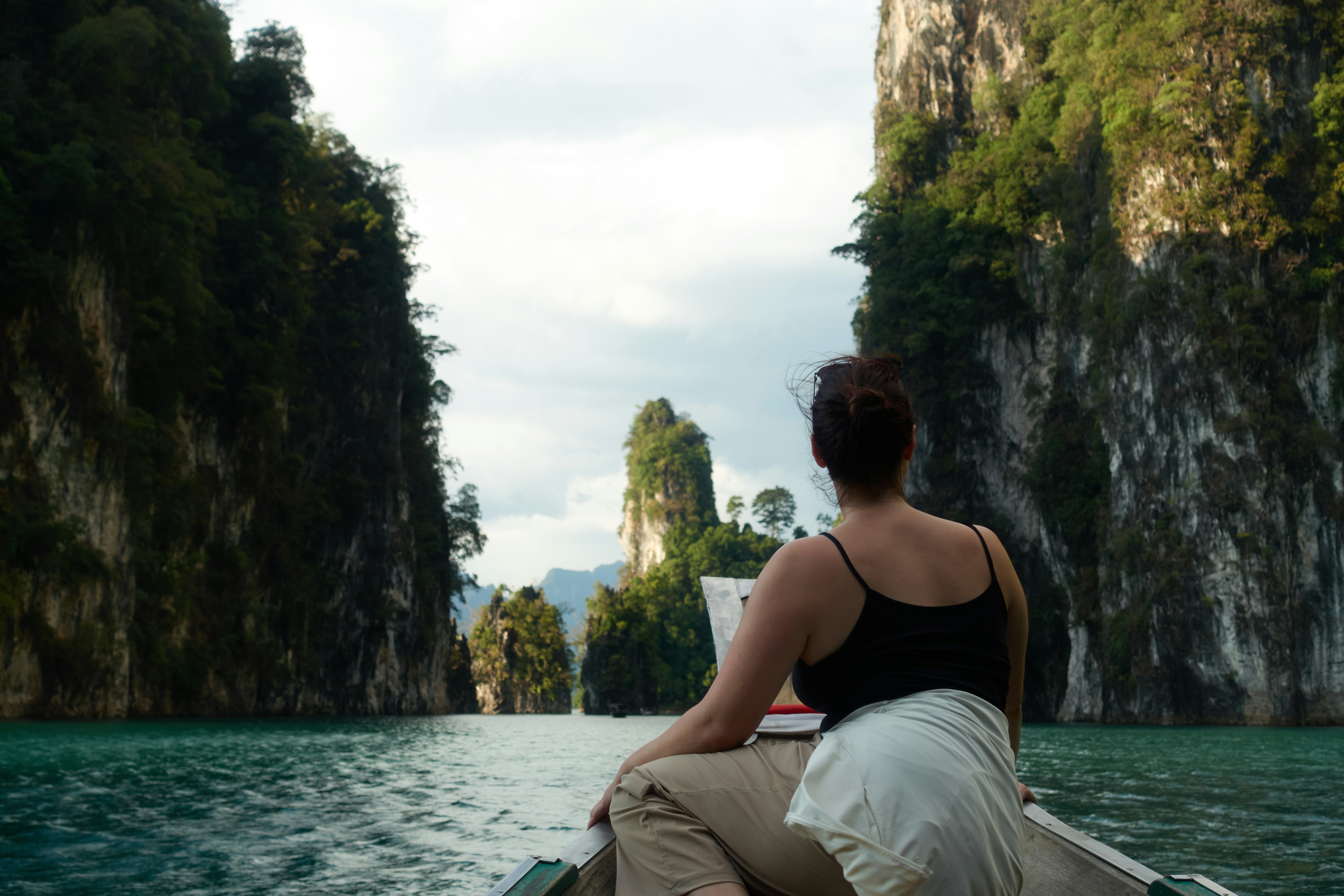 Woman in boat sailing through limestone cliffs